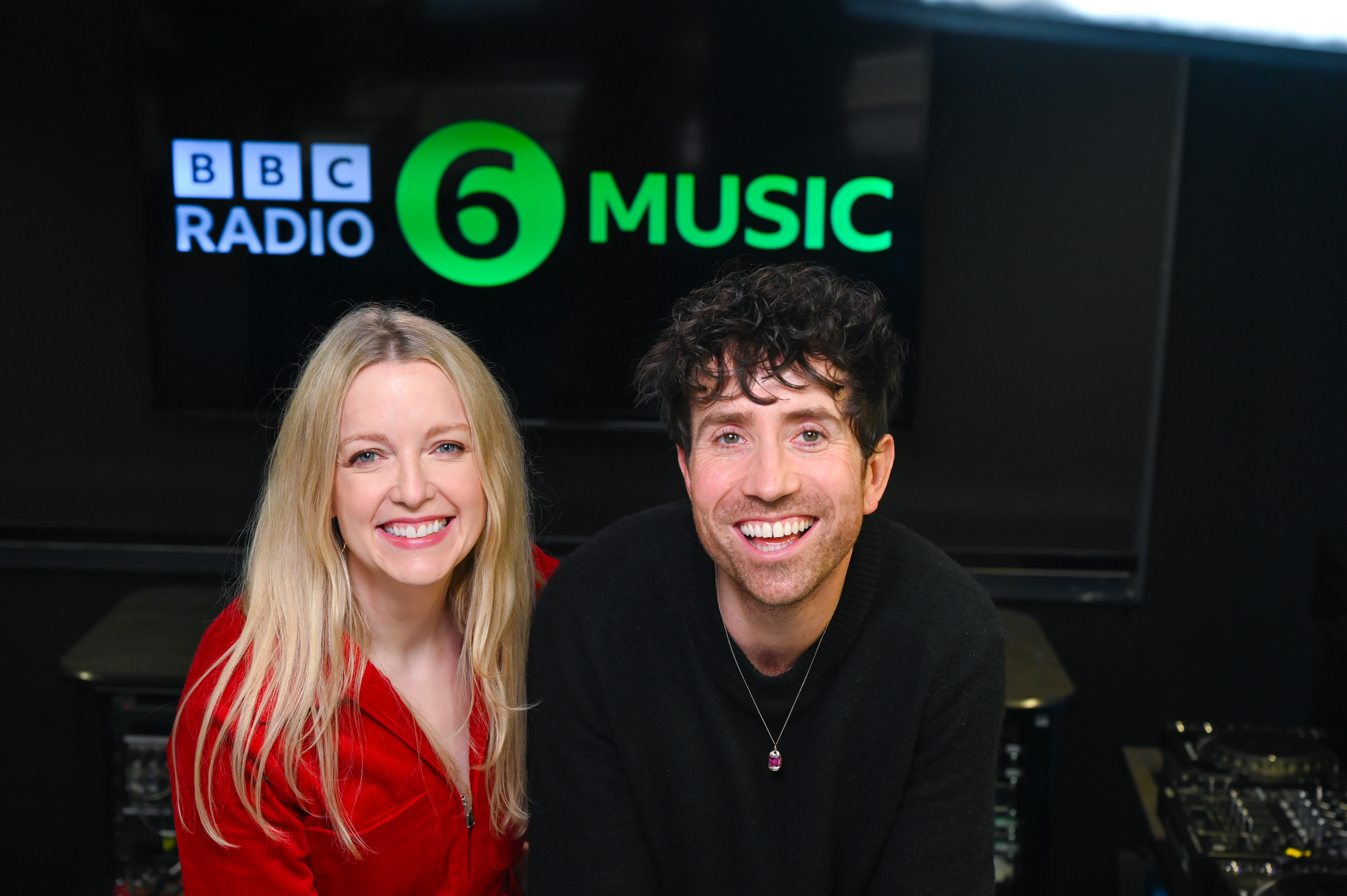 Lauren Laverne and Nick Grimshaw smile at the camera in the BBC Radio 6 Music studio