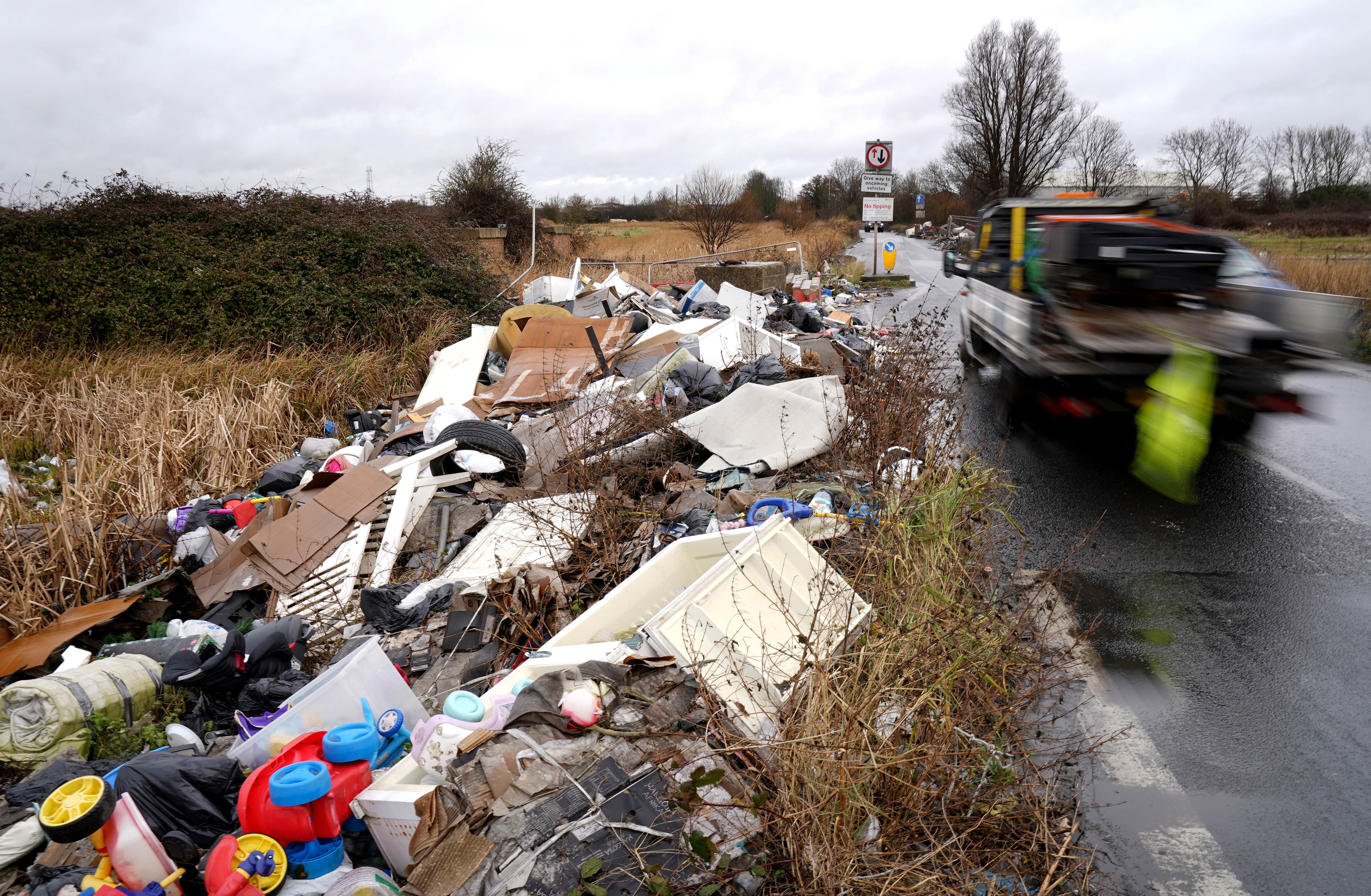 Rubbish dumped at side of a road, as a truck passes