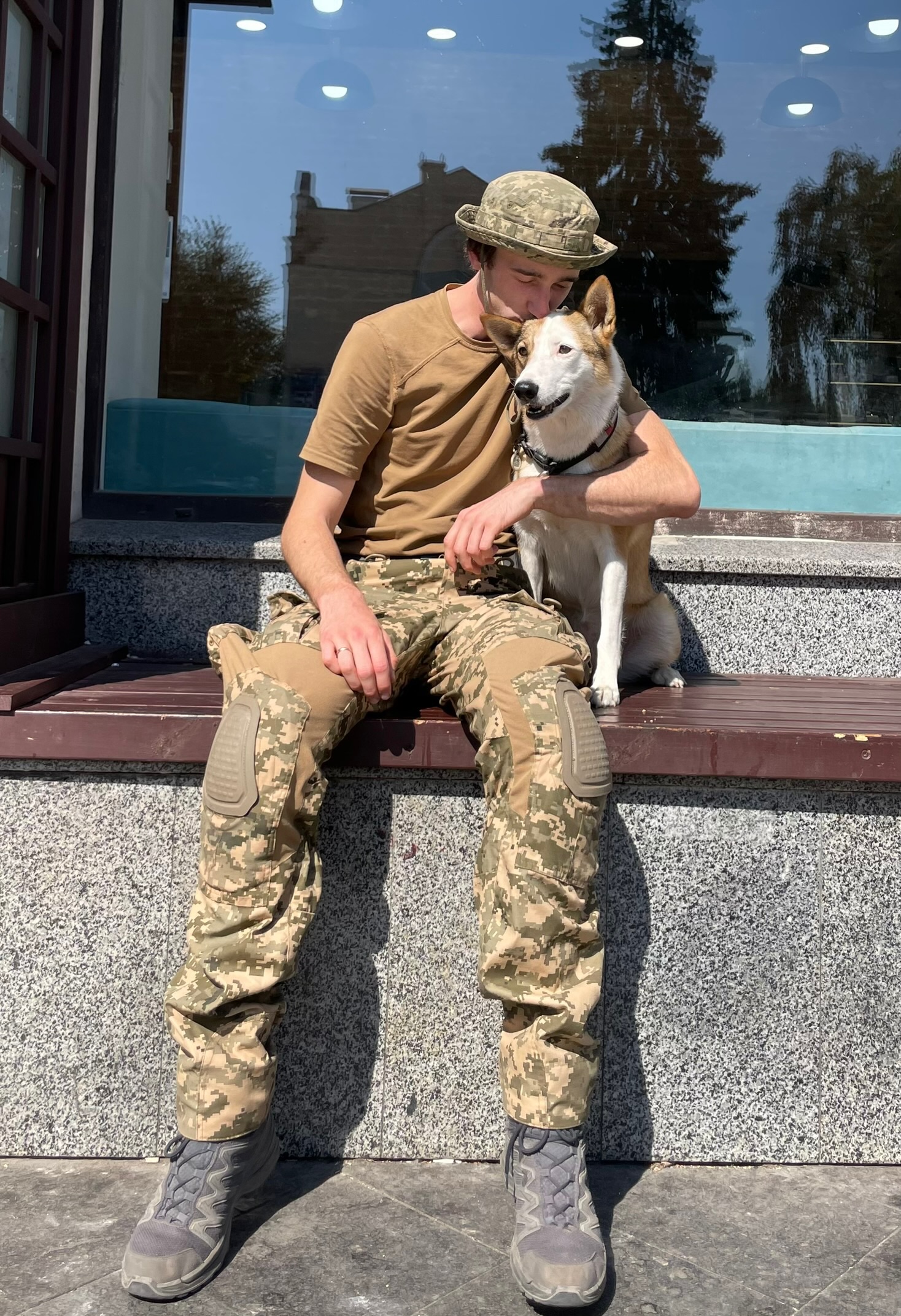 A soldier in camouflage hugging a dog