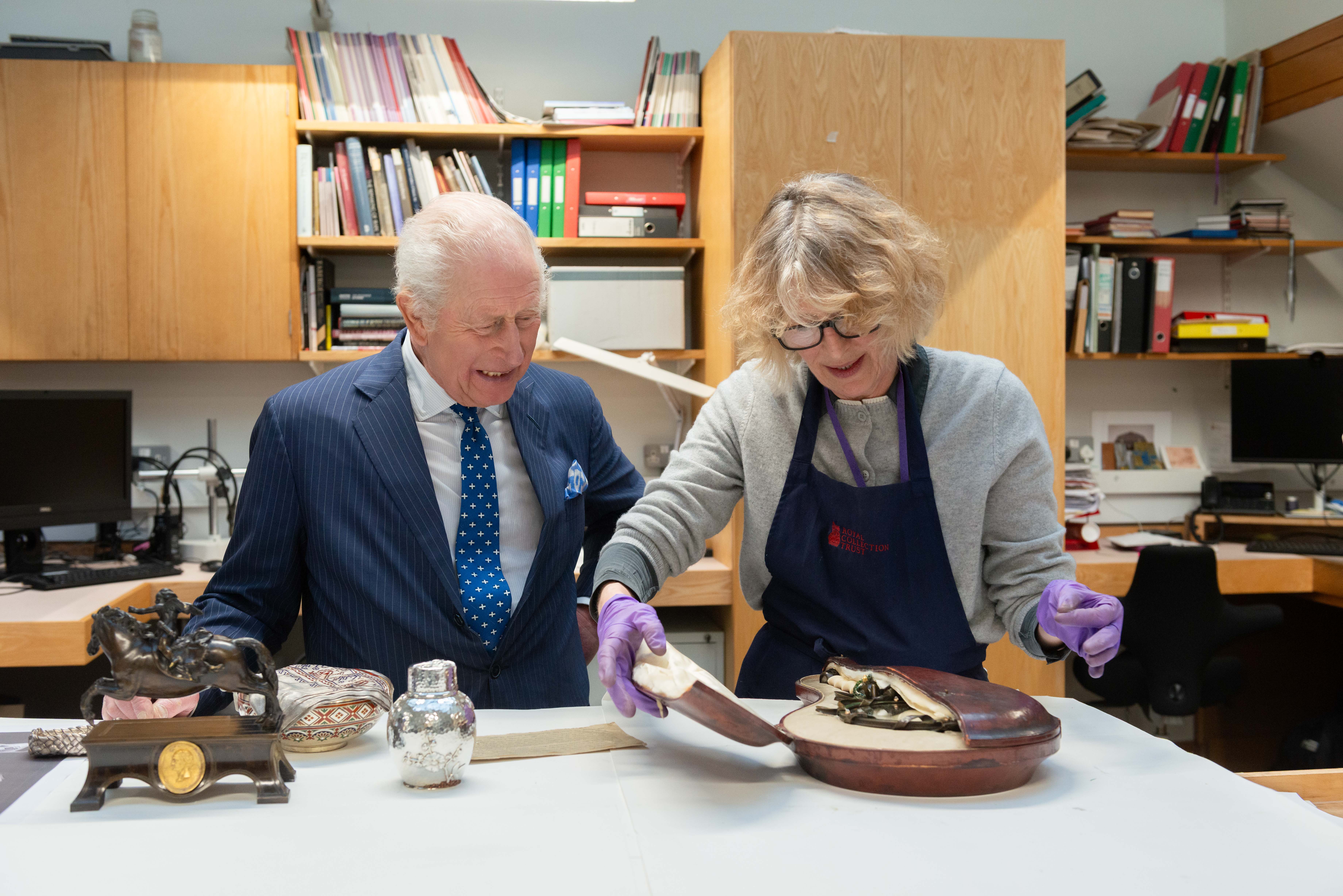 The King with senior metalwork conservator Sophy Wills as they examine a mirror