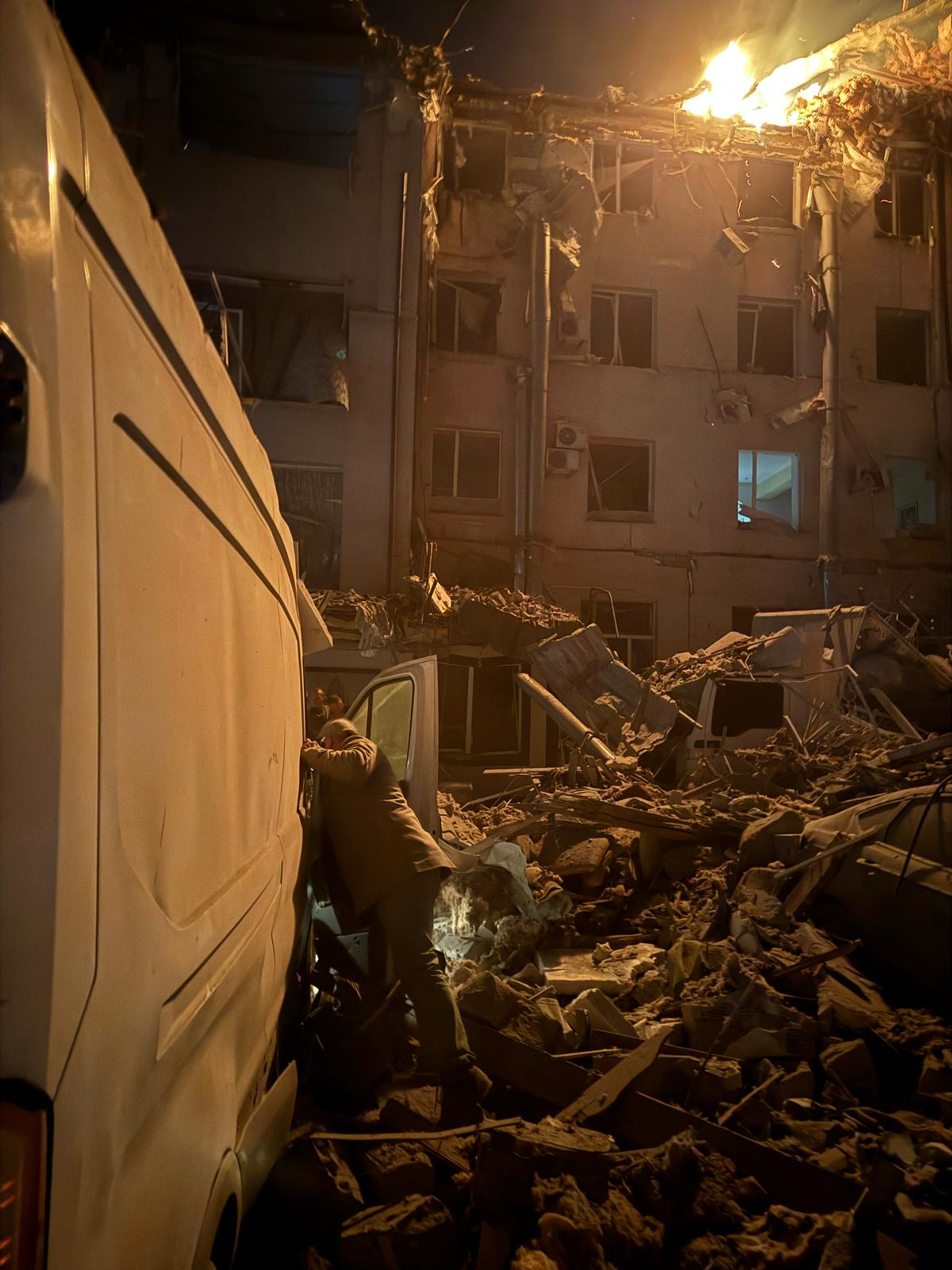 Man looking inside a van surrounded by rubble and debris following an airstrike in Ukraine