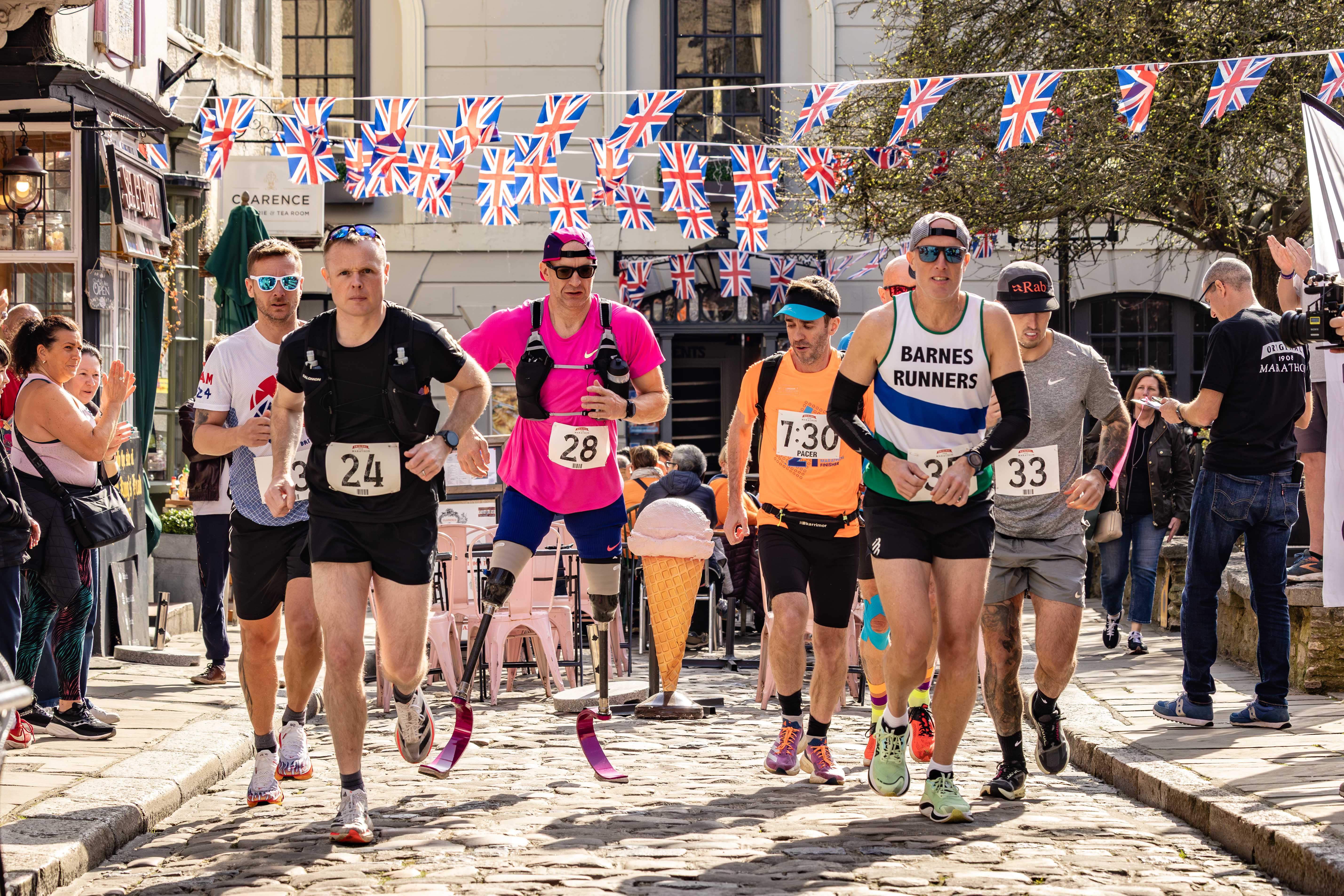 Paralympian Richard Whitehead, wearing a pink shirt and prosthetic legs, running a marathon