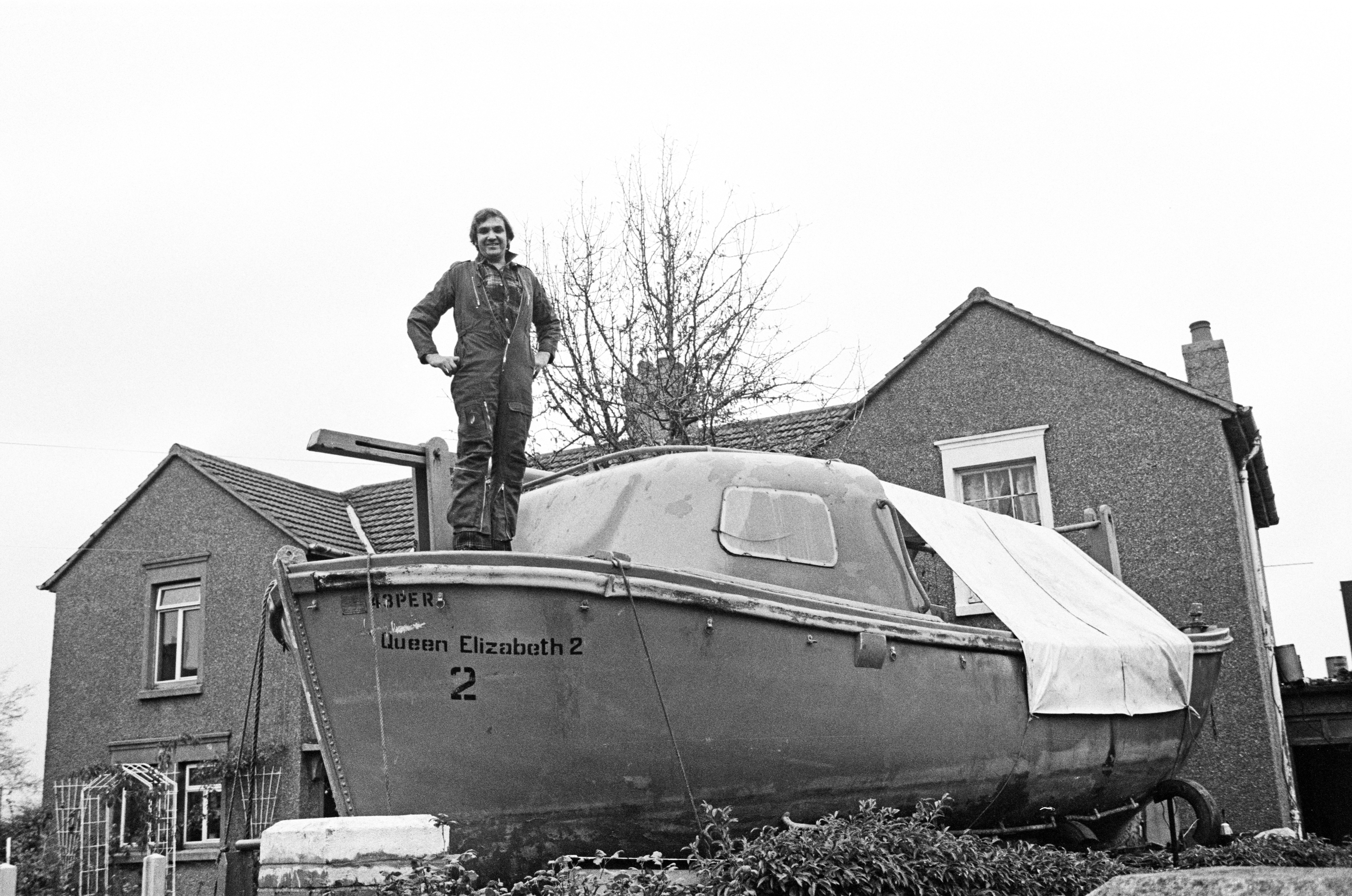 A man stands on top of a lifeboat