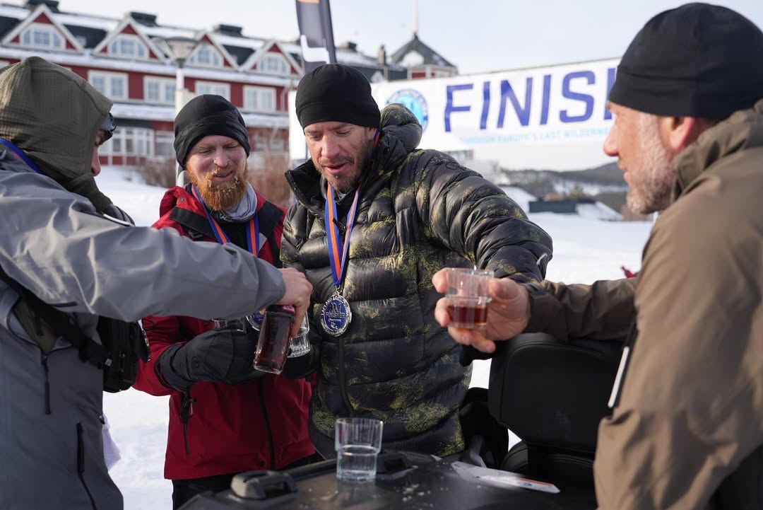 A group of men at a finish line with whiskey