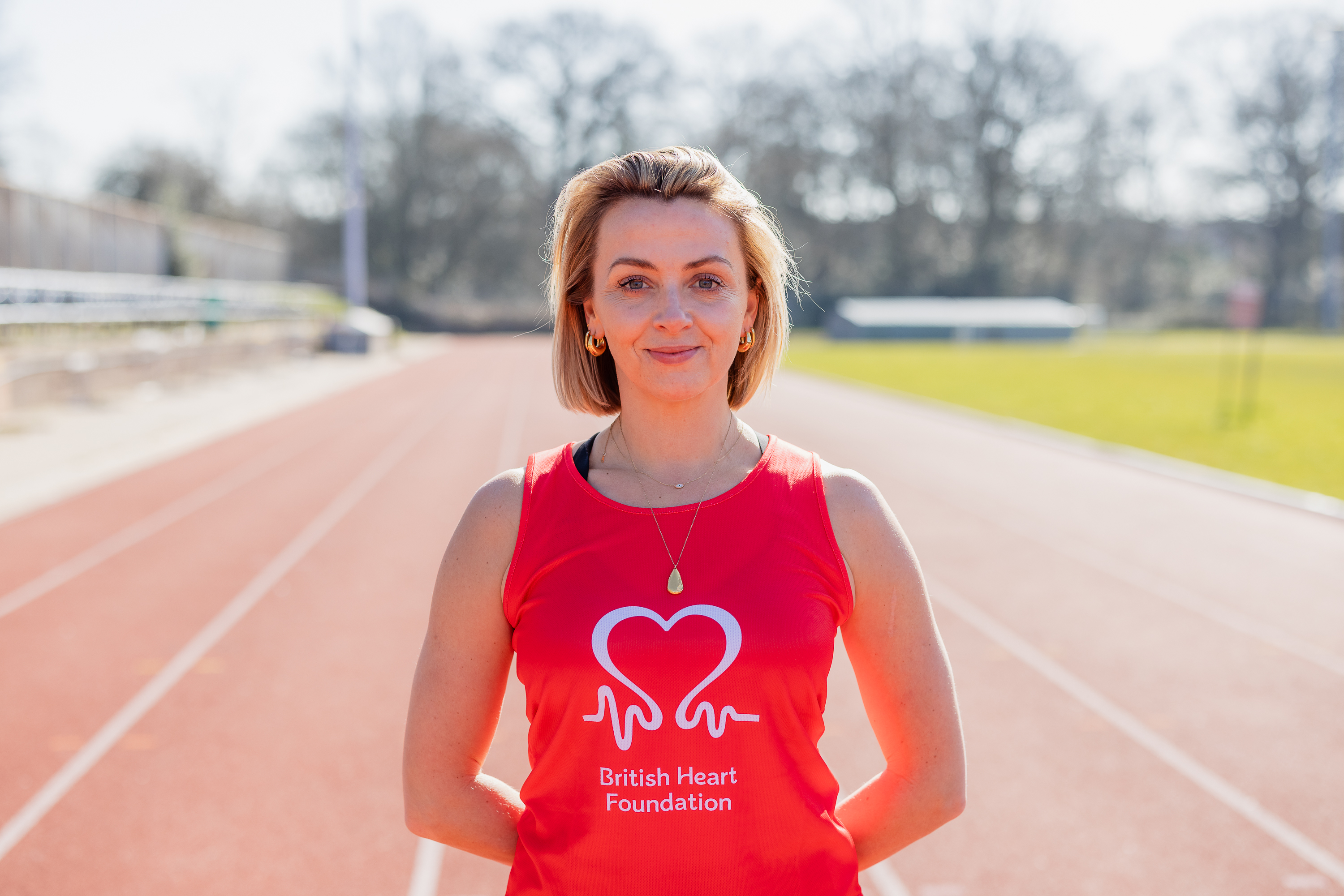 Lisa McGrillis wearing a red and white British Heart Foundation running vest at Tooting Bec track in south London