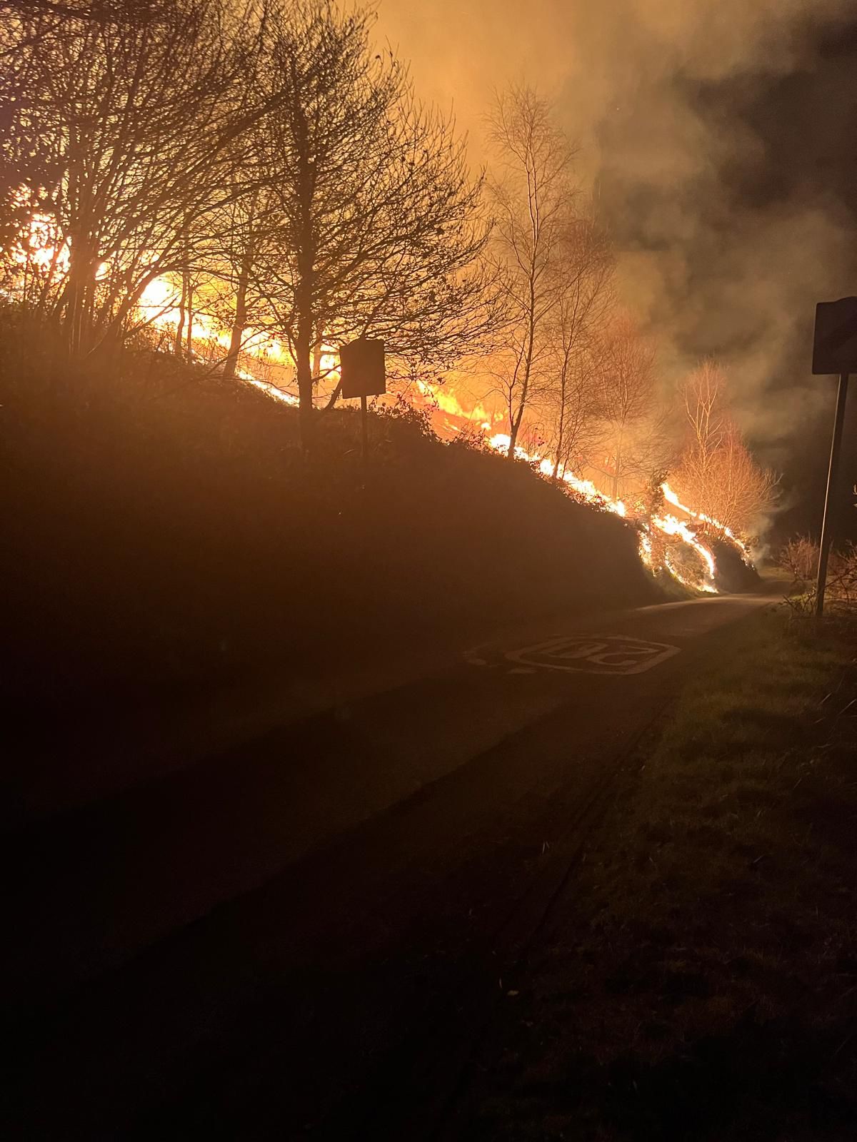 A wildfire on banking next to a road in the dark