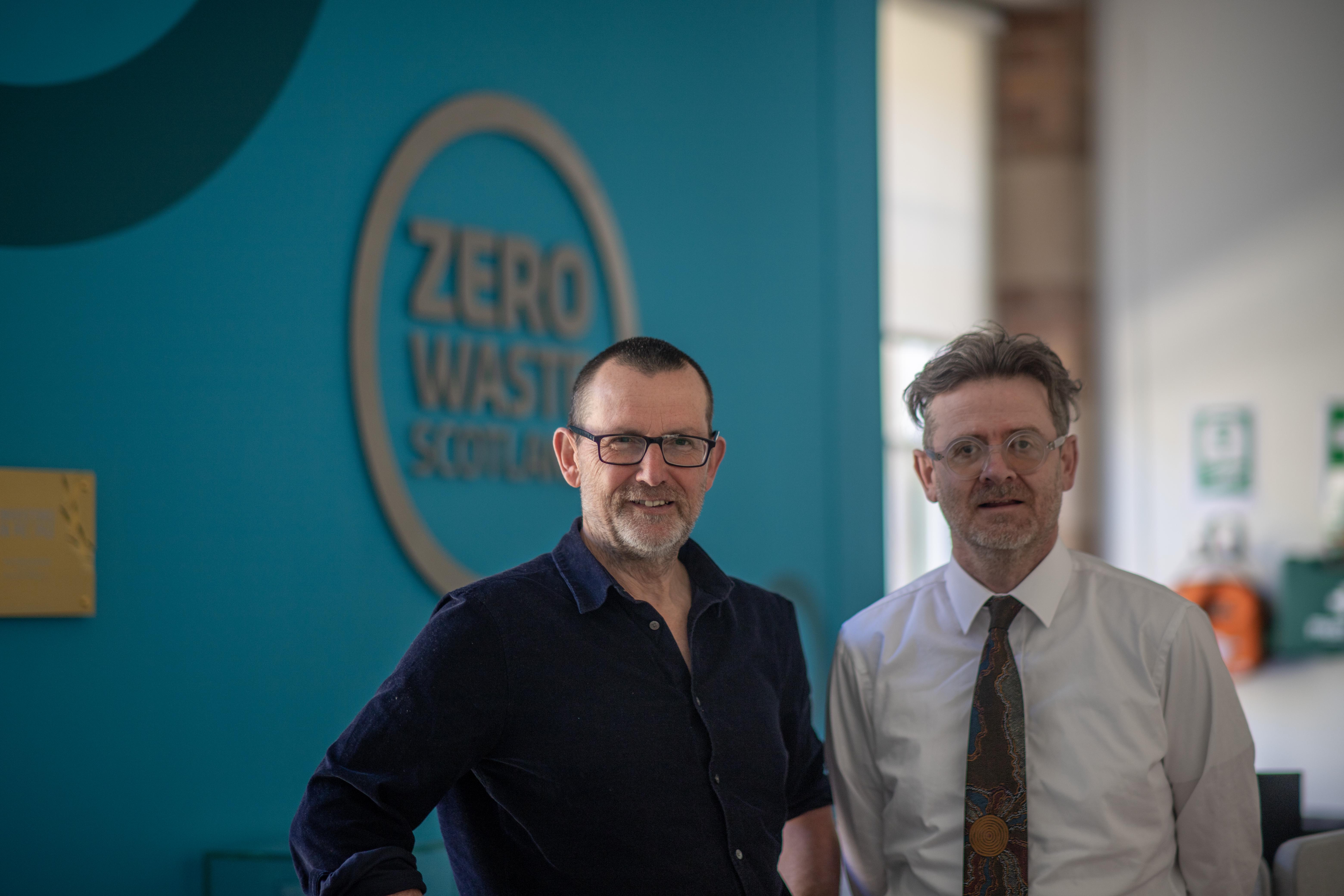 Iain Gulland and Neil McInroy in an office, in front of a wall with the Zero Waste Scotland logo on it