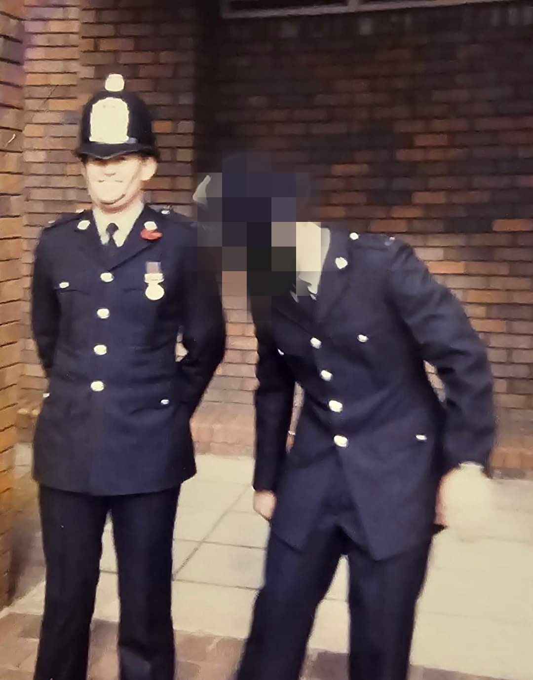 Bob wearing police uniform and standing beside a colleague, whose face has been blurred 