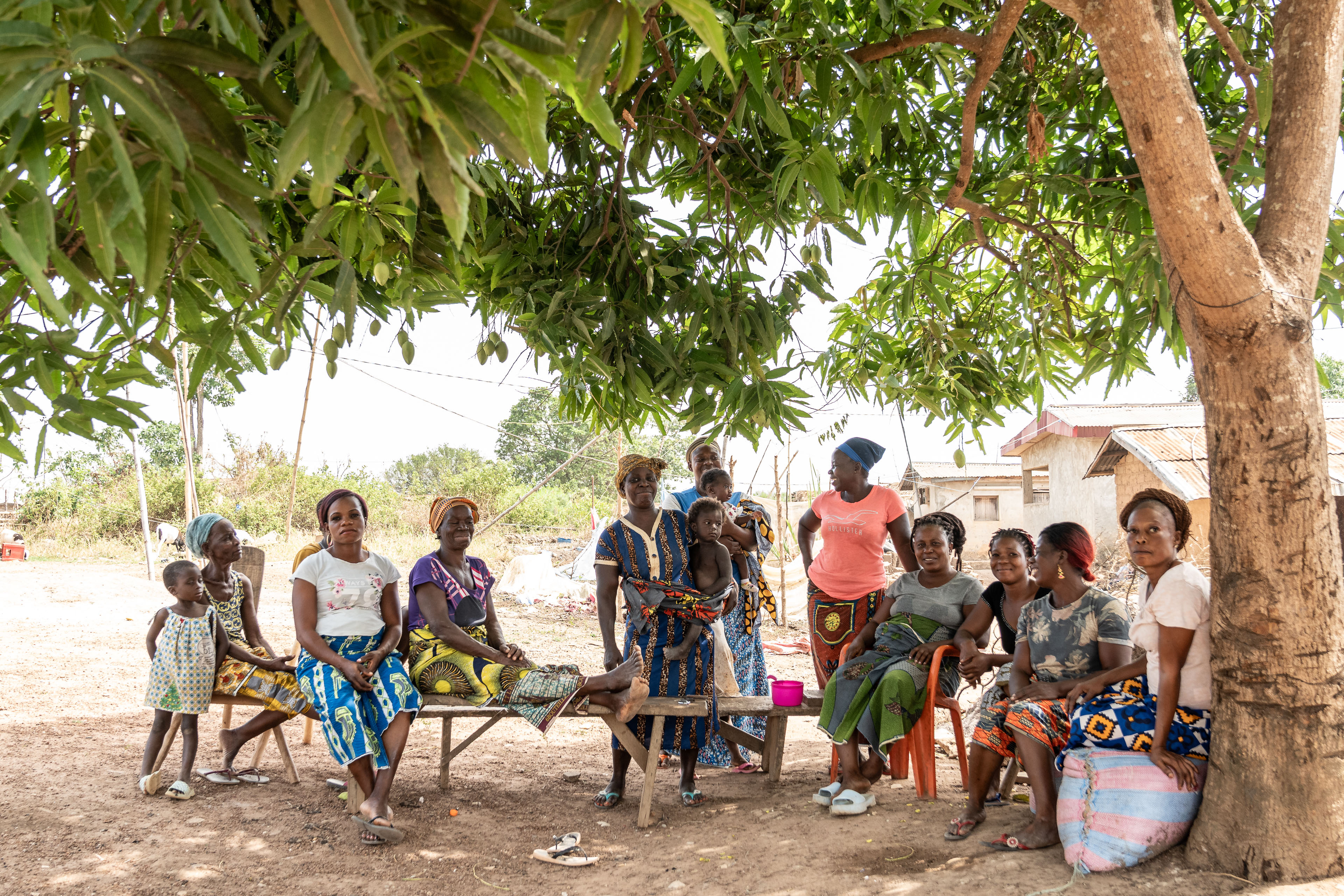 Mothers and their children sit in the shade in the village of Douele, the Bafing-Tonpki region, Ivory Coast in February 2025. (Chris Terry/PA)