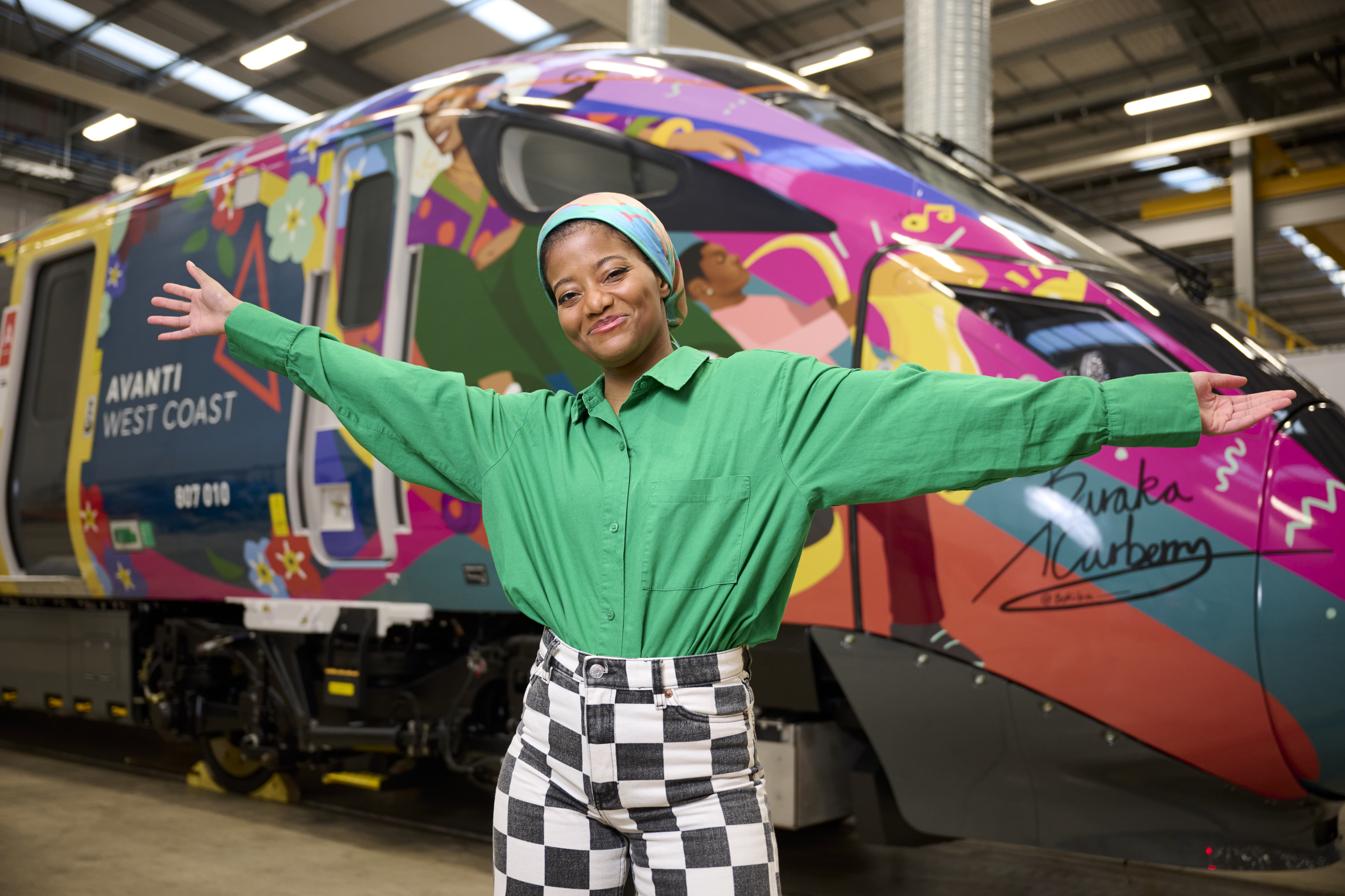 Artist Baraka Carberry standing in front of a train wrapped in her design