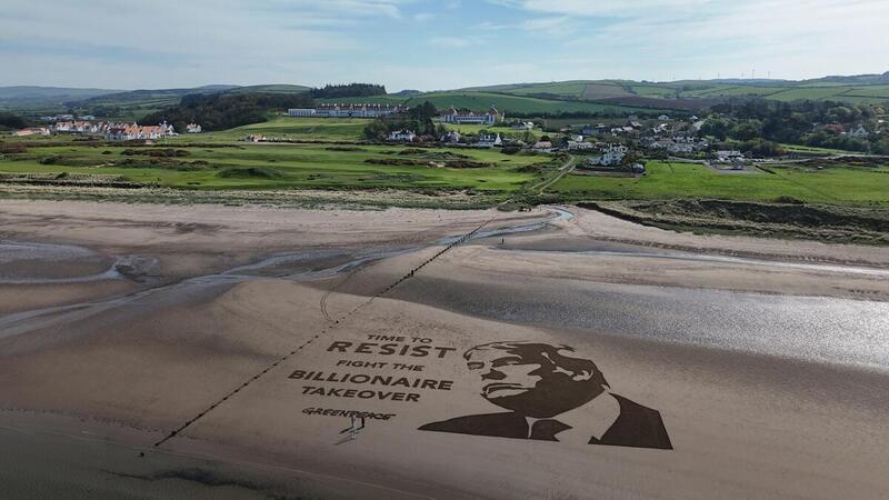 Aerial view of artwork on the sand, with a golf course beyond