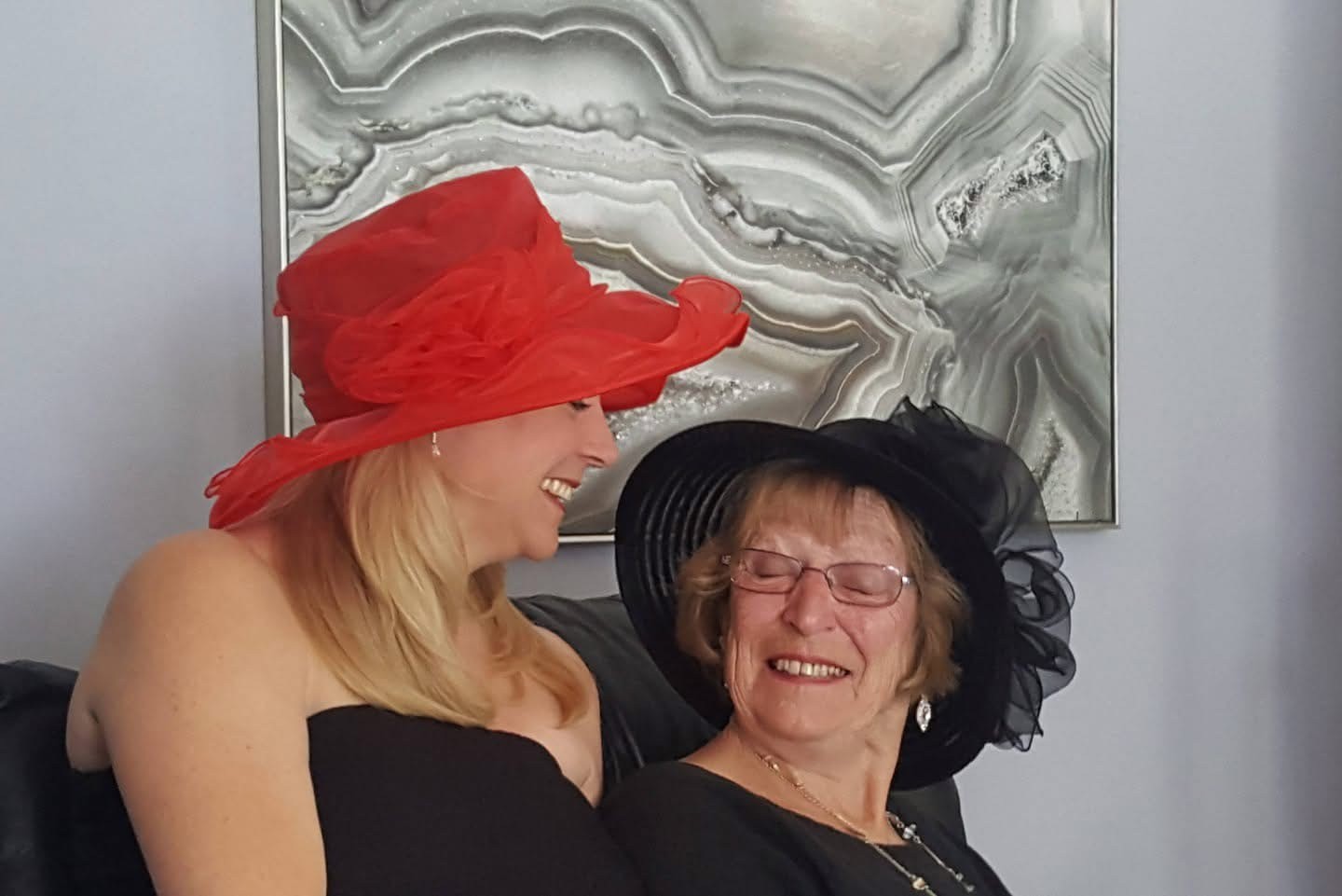 Helen and her mother sitting close together, both smiling as they turn to look at each other 