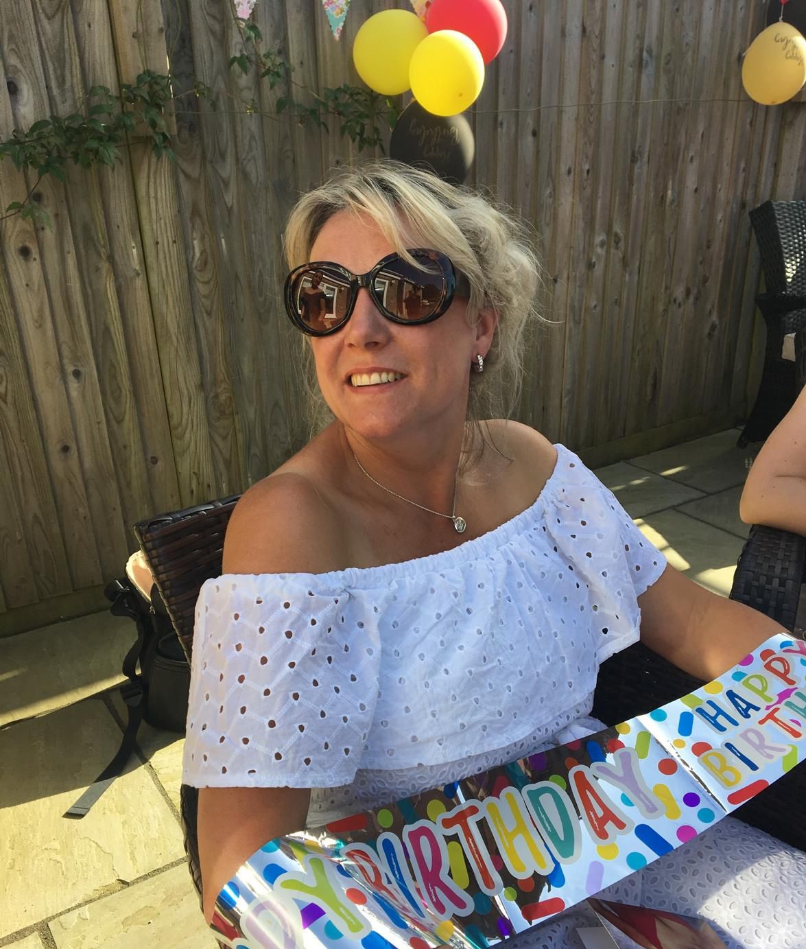 Helen sitting in a chair wearing sunglasses and smiling 