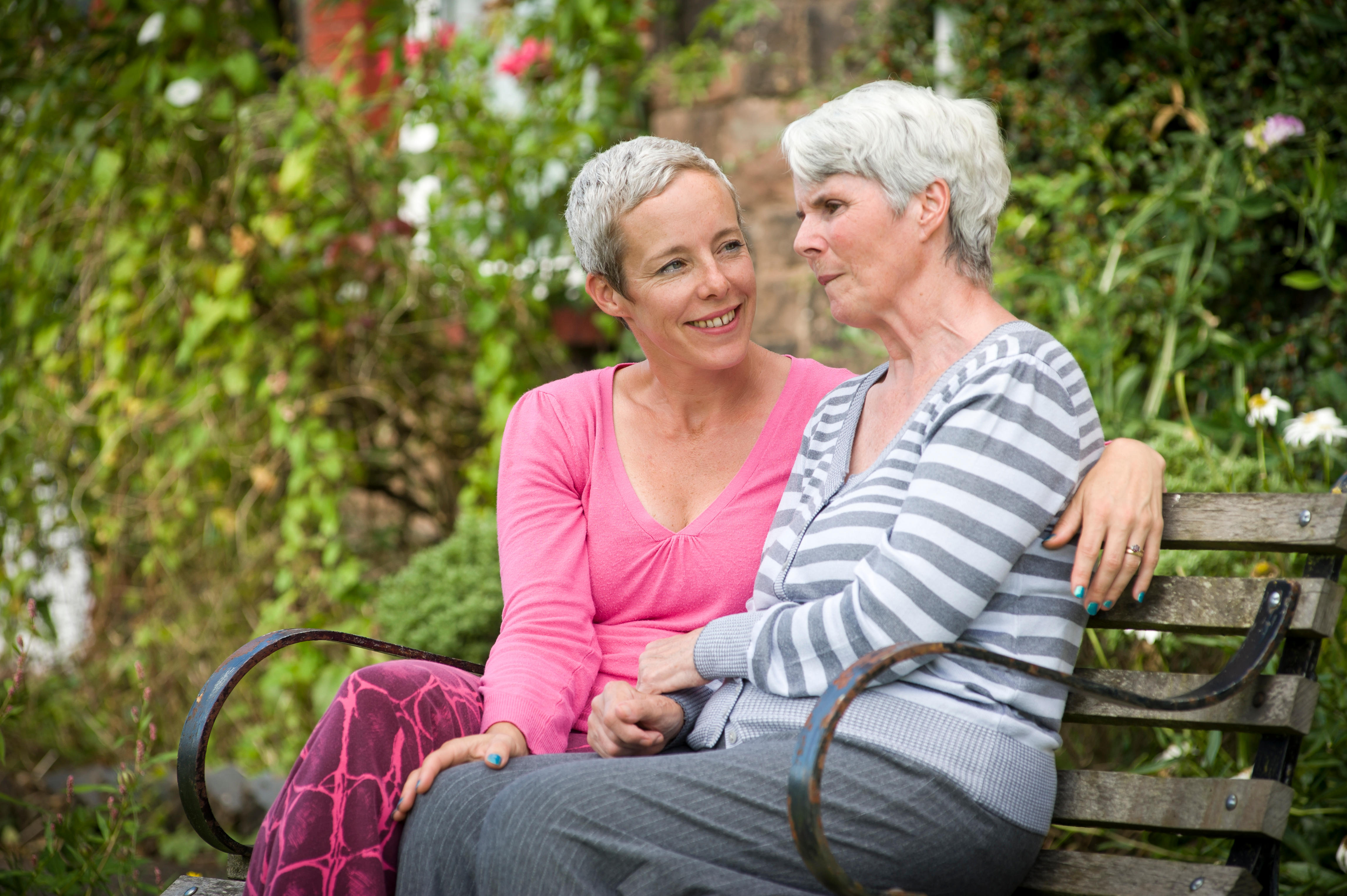 An adult woman sat on a bench with her mother who has Alzheimer's 