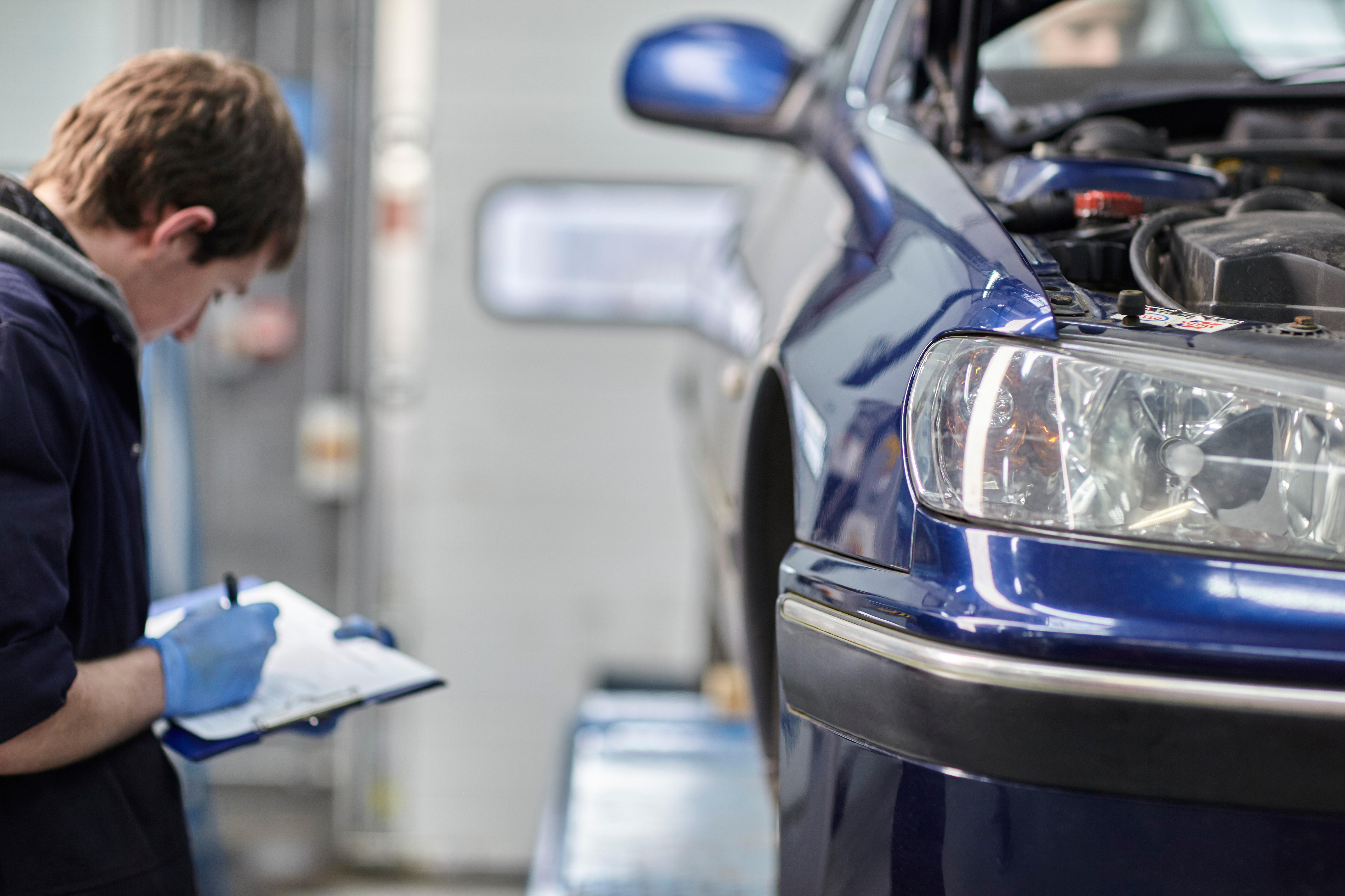 A mechanic checking a car and making notes