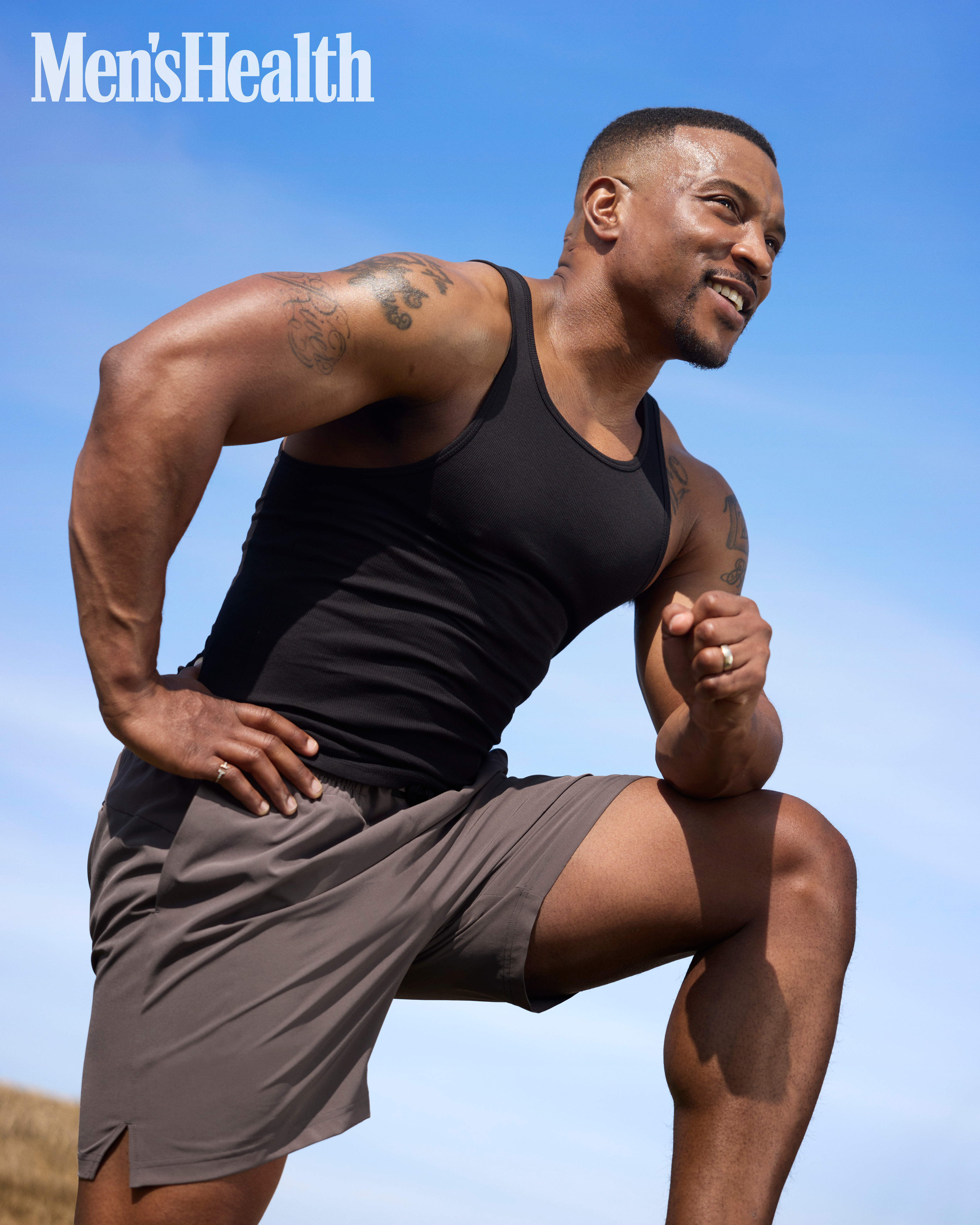 Ashley Walters smiling while wearing black vest top and shorts
