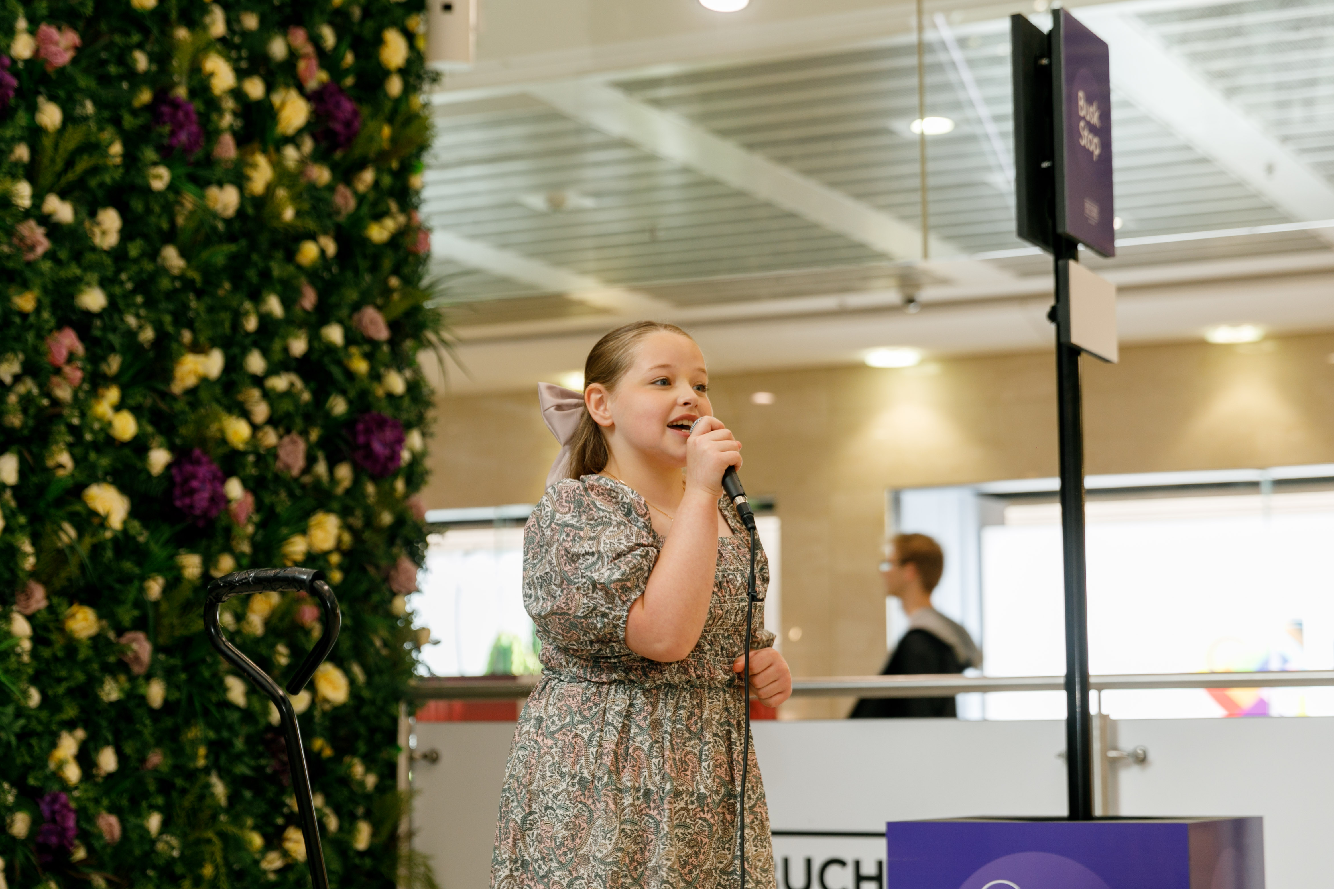 Rachel Ronnie singing into a microphone in a shopping centre