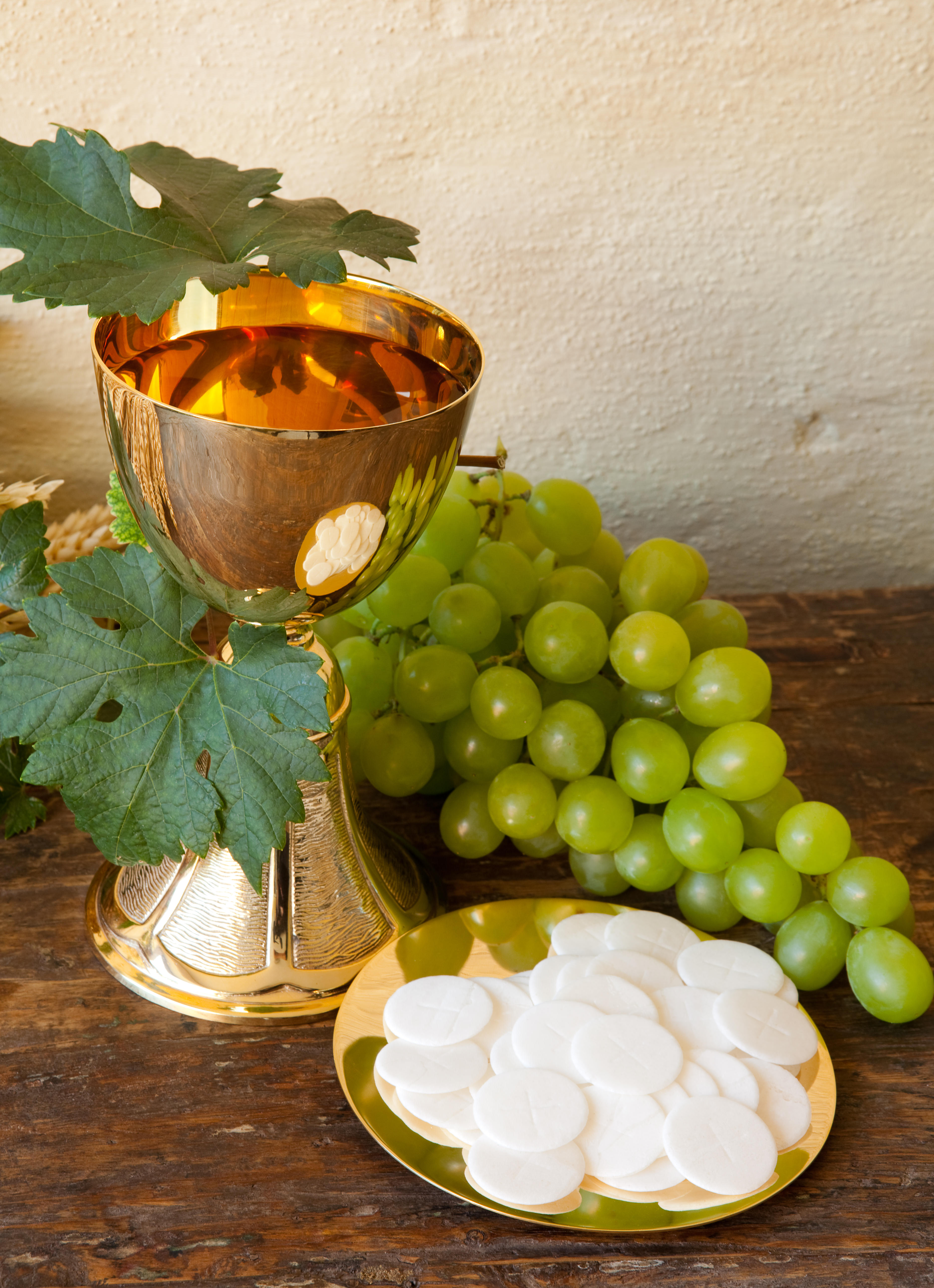 showing a golden chalice with grapes and bread wafers