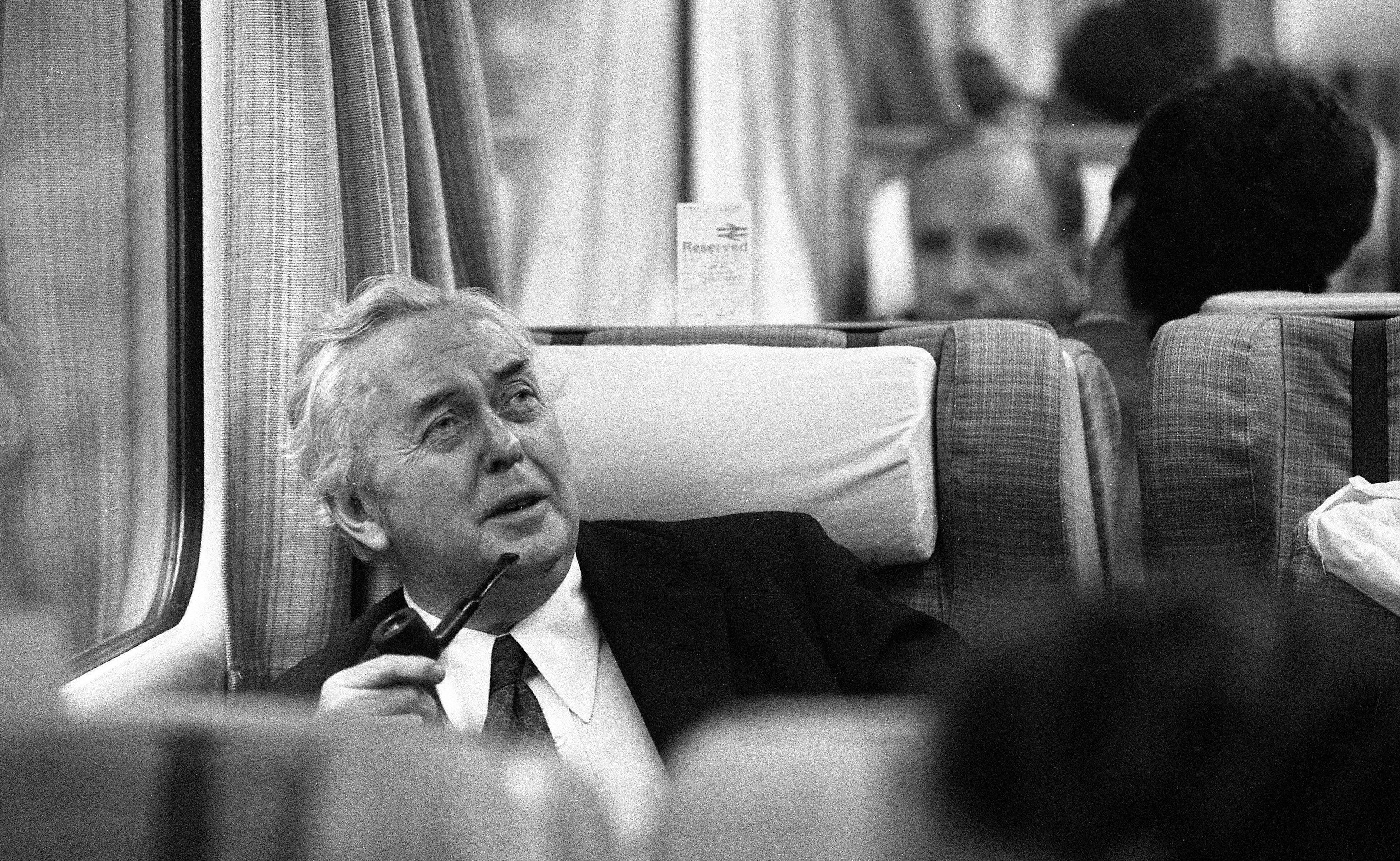 Harold Wilson sitting on a train holding his pipe