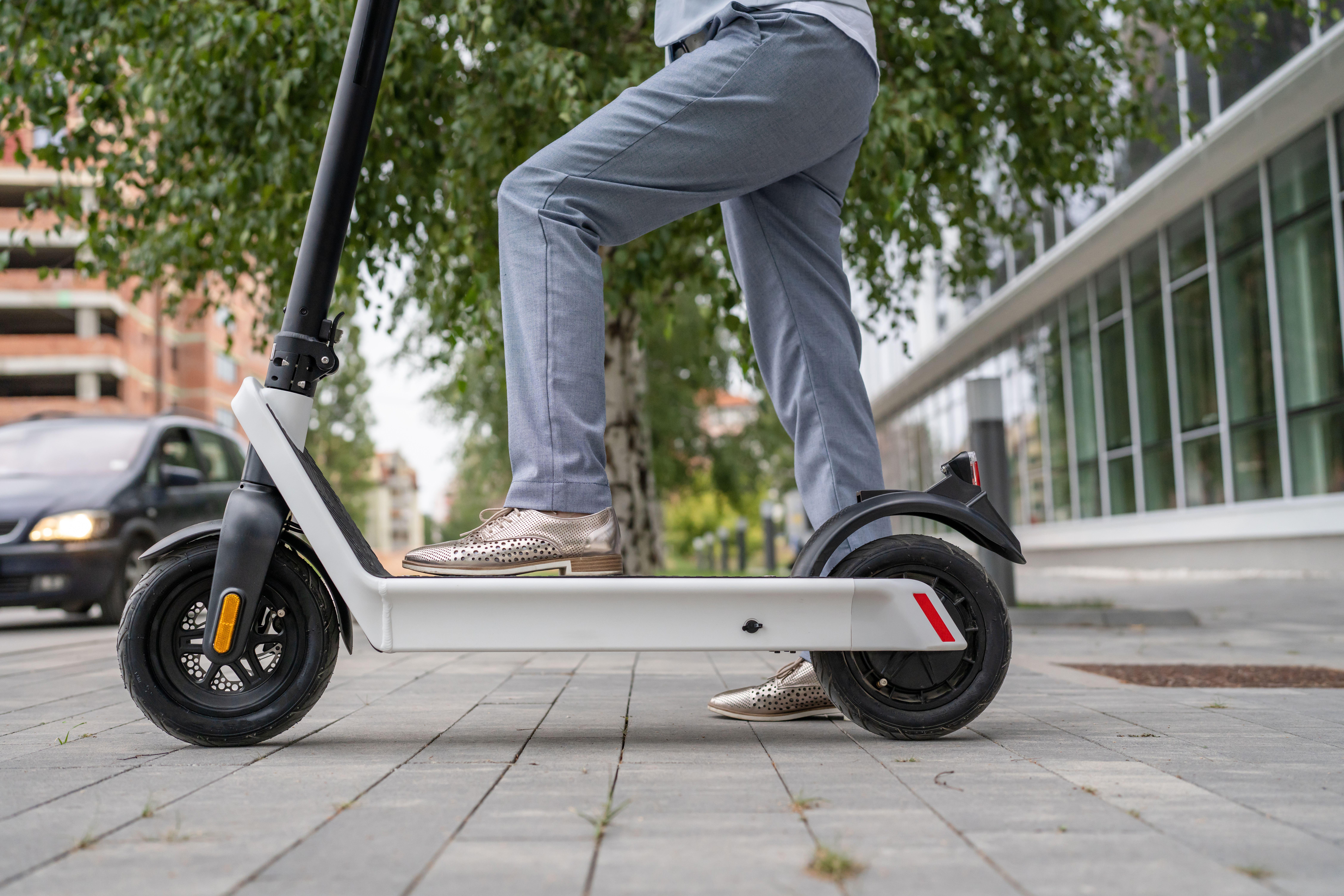 Legs of person standing by an e-scooter