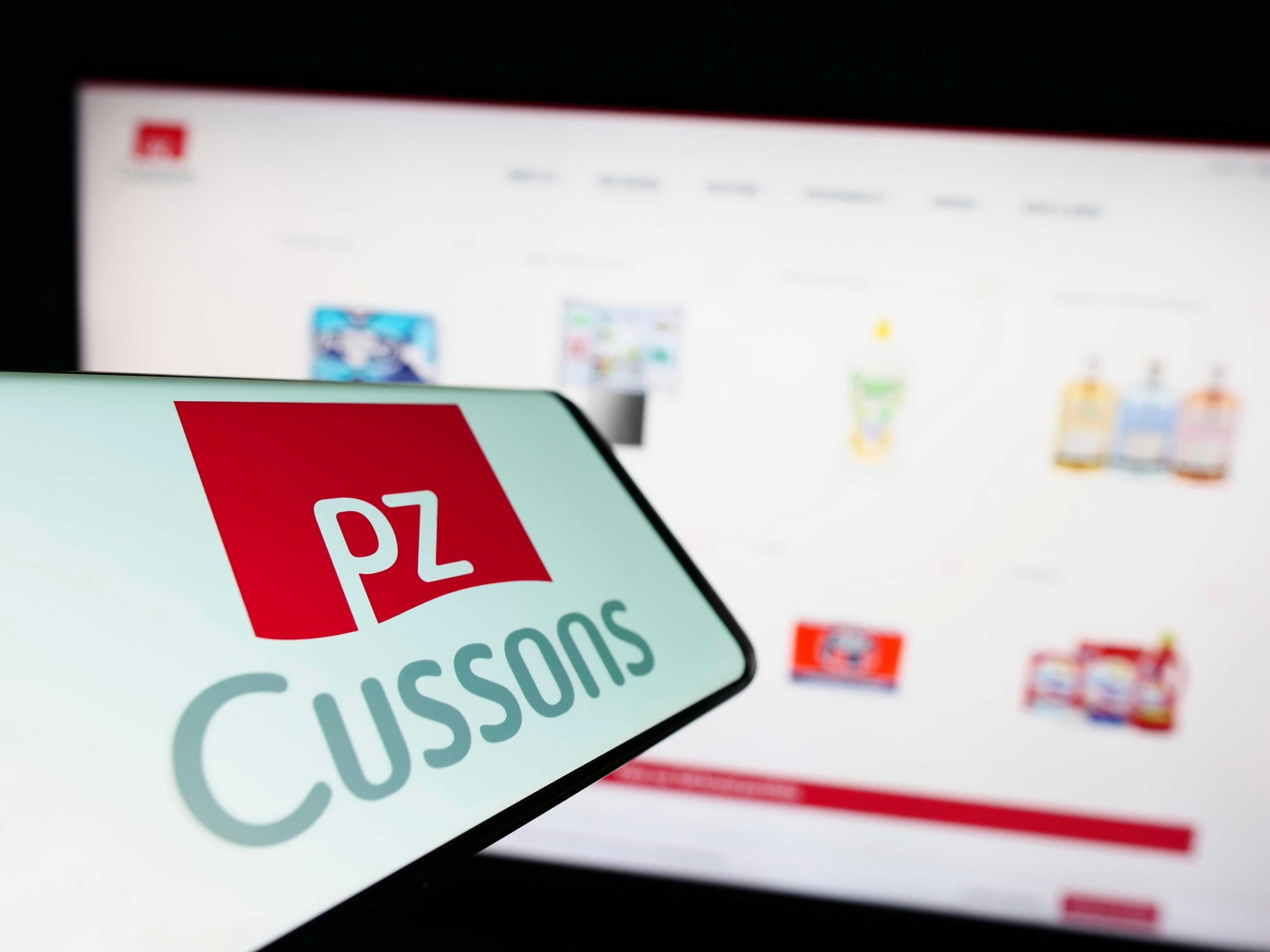 A smartphone with logo of PZ Cussons on screen in front of business website