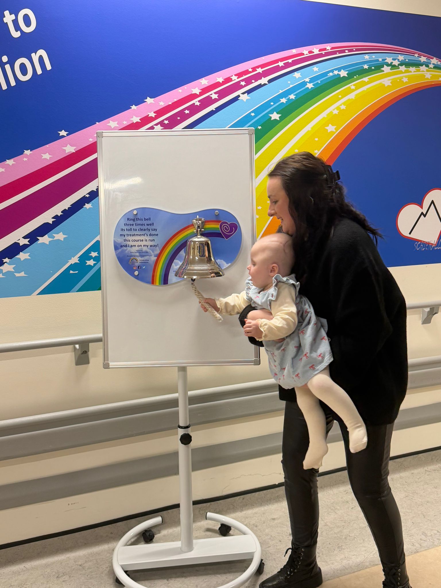 Emilie Sime rings a bell, while being held by her mother