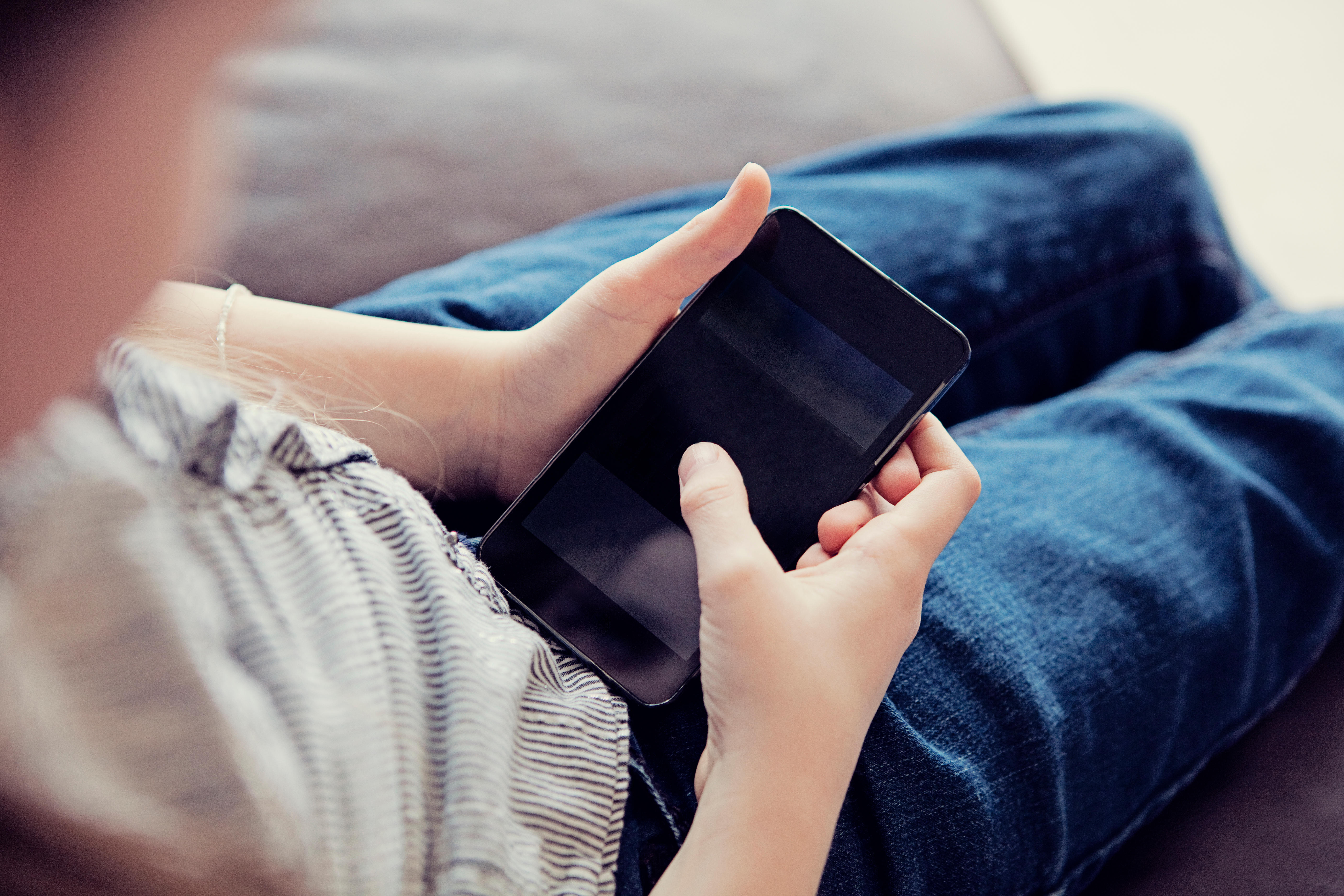 Over the shoulder view of a child using a smartphone