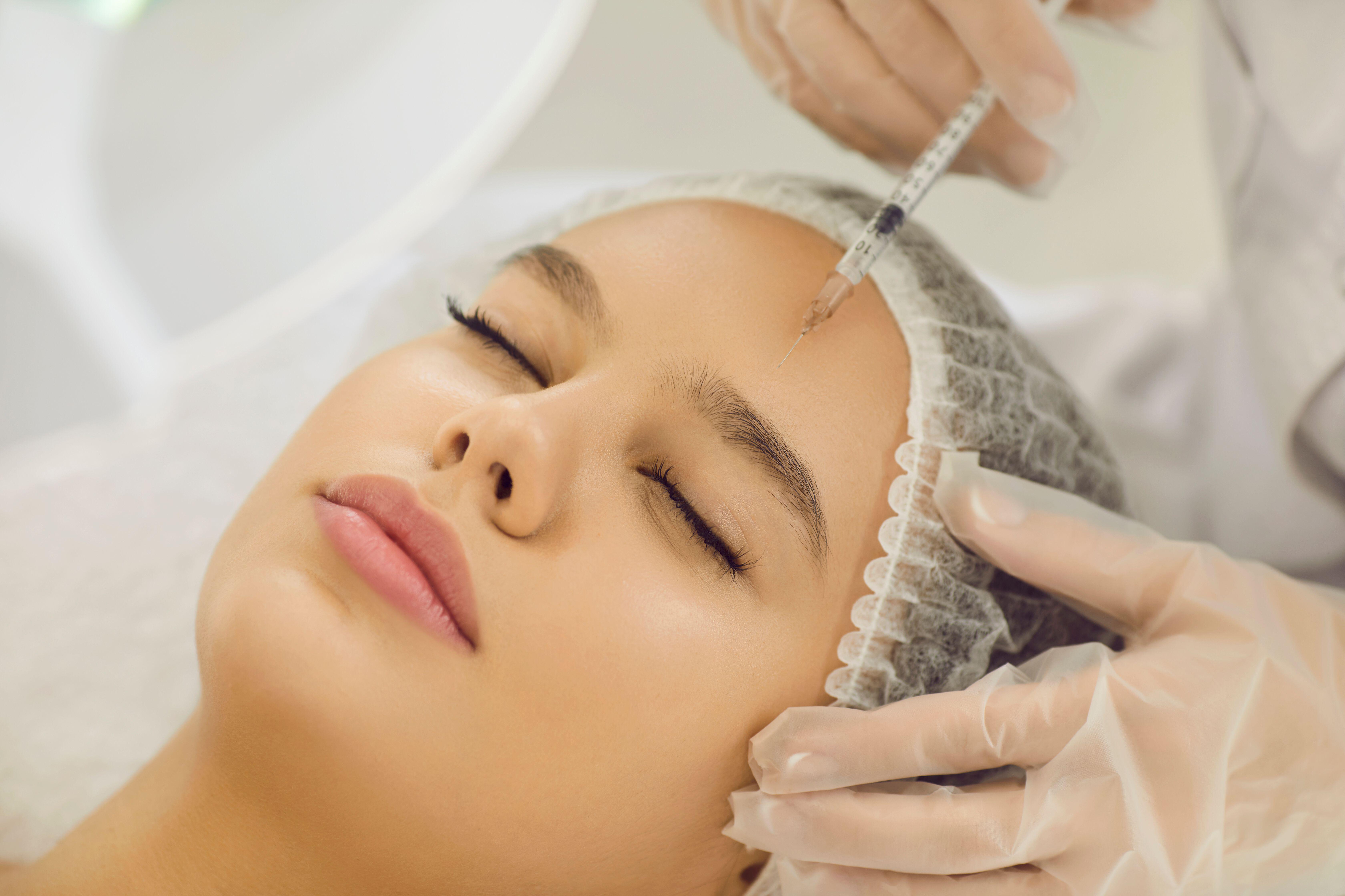 A woman has a filler injection in her forehead