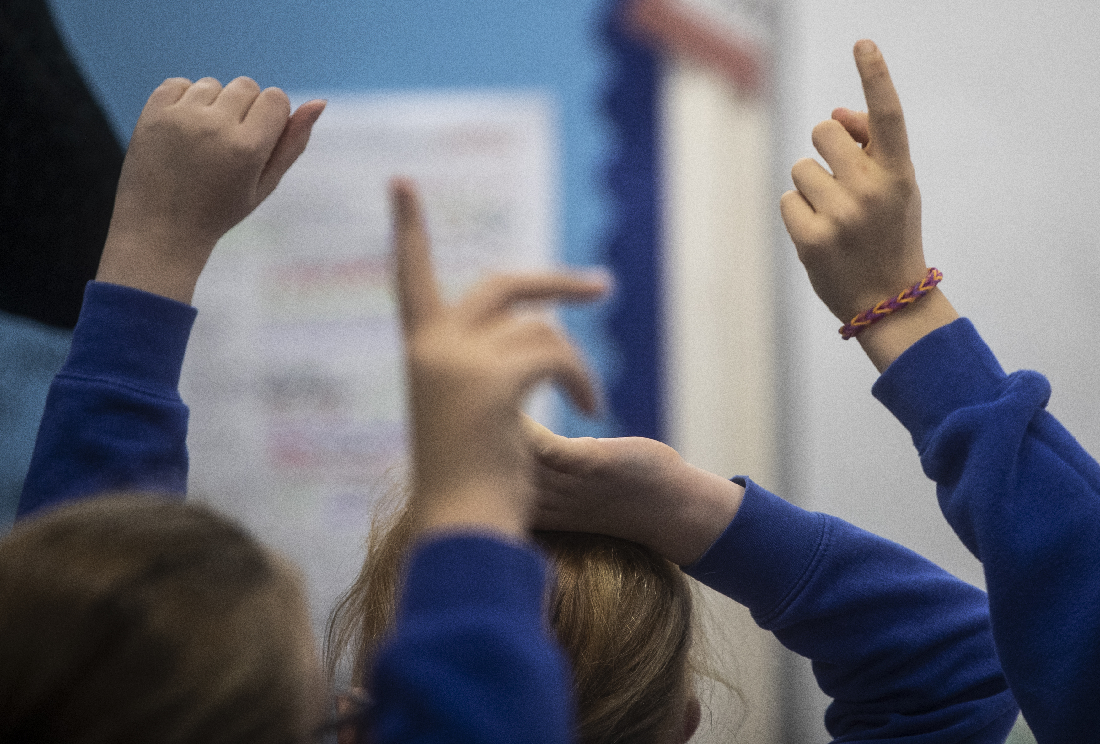 The raised arms of children in class