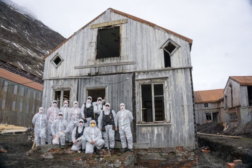 A team of people in overalls and protective masks in front of Shackleton Villa