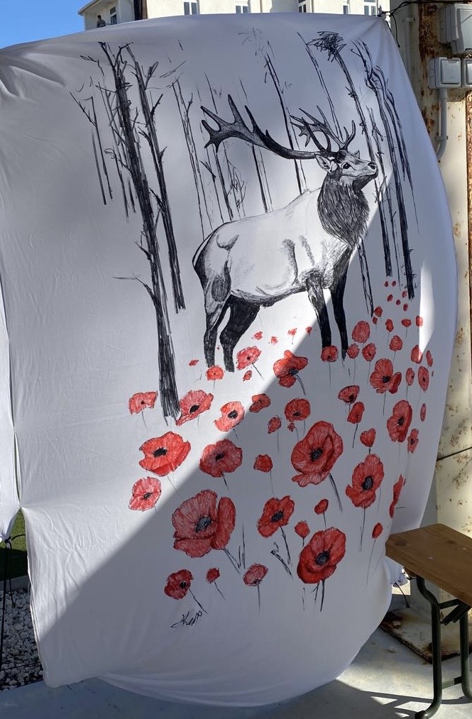 A blanket decorated with an image of a stag standing among poppies