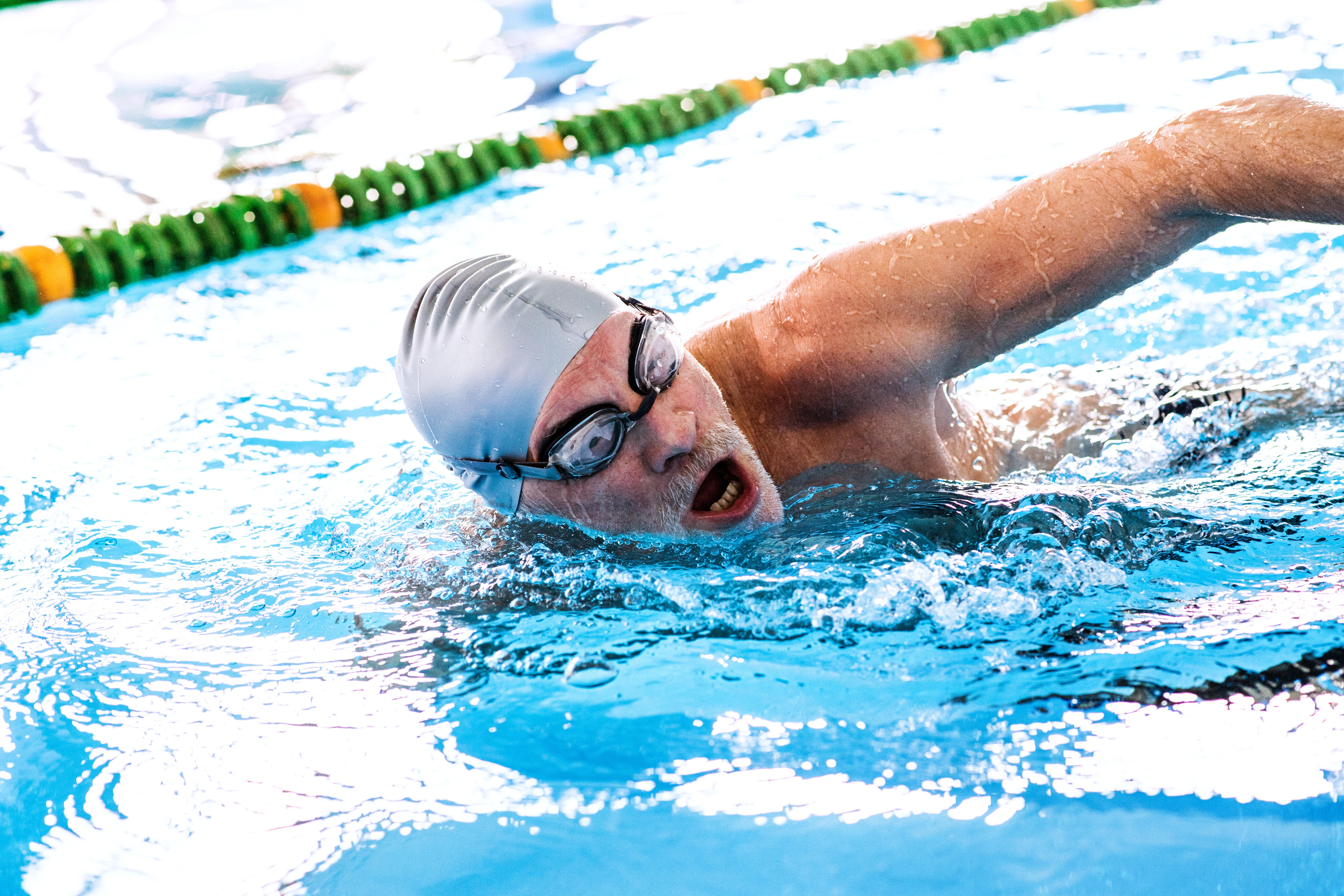 Senior man swimming in an indoor swimming pool.