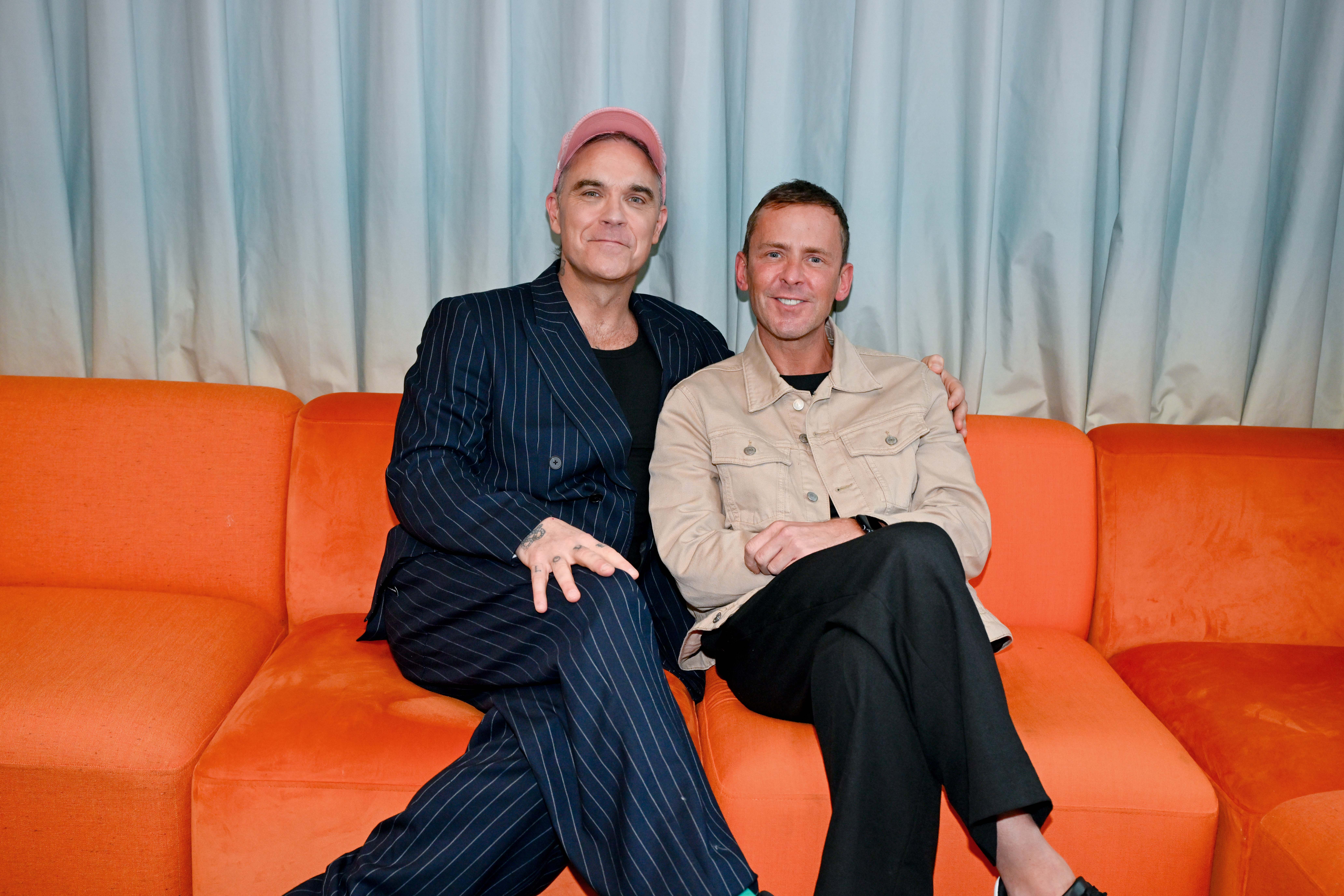 Robbie Williams and Scott Mills sit together on a sofa