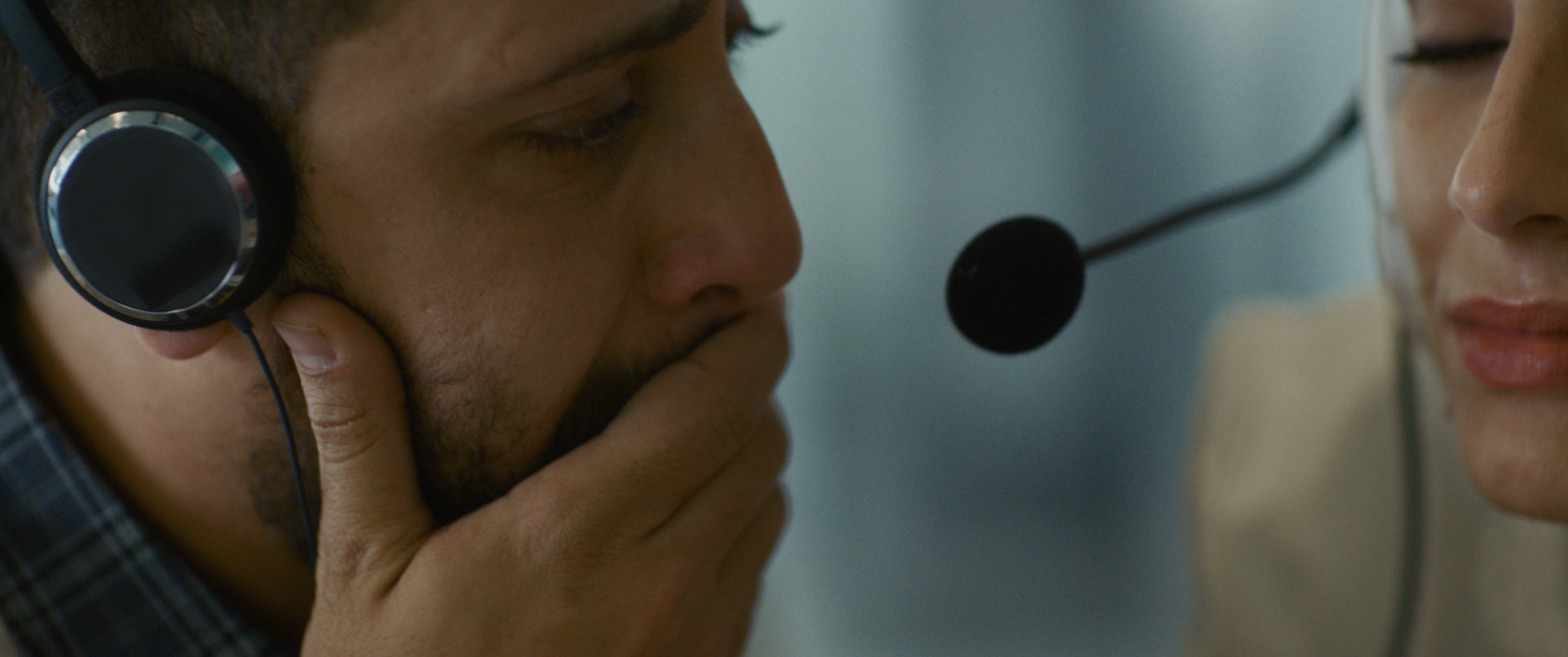 A man listens to a phone call while wearing a headset