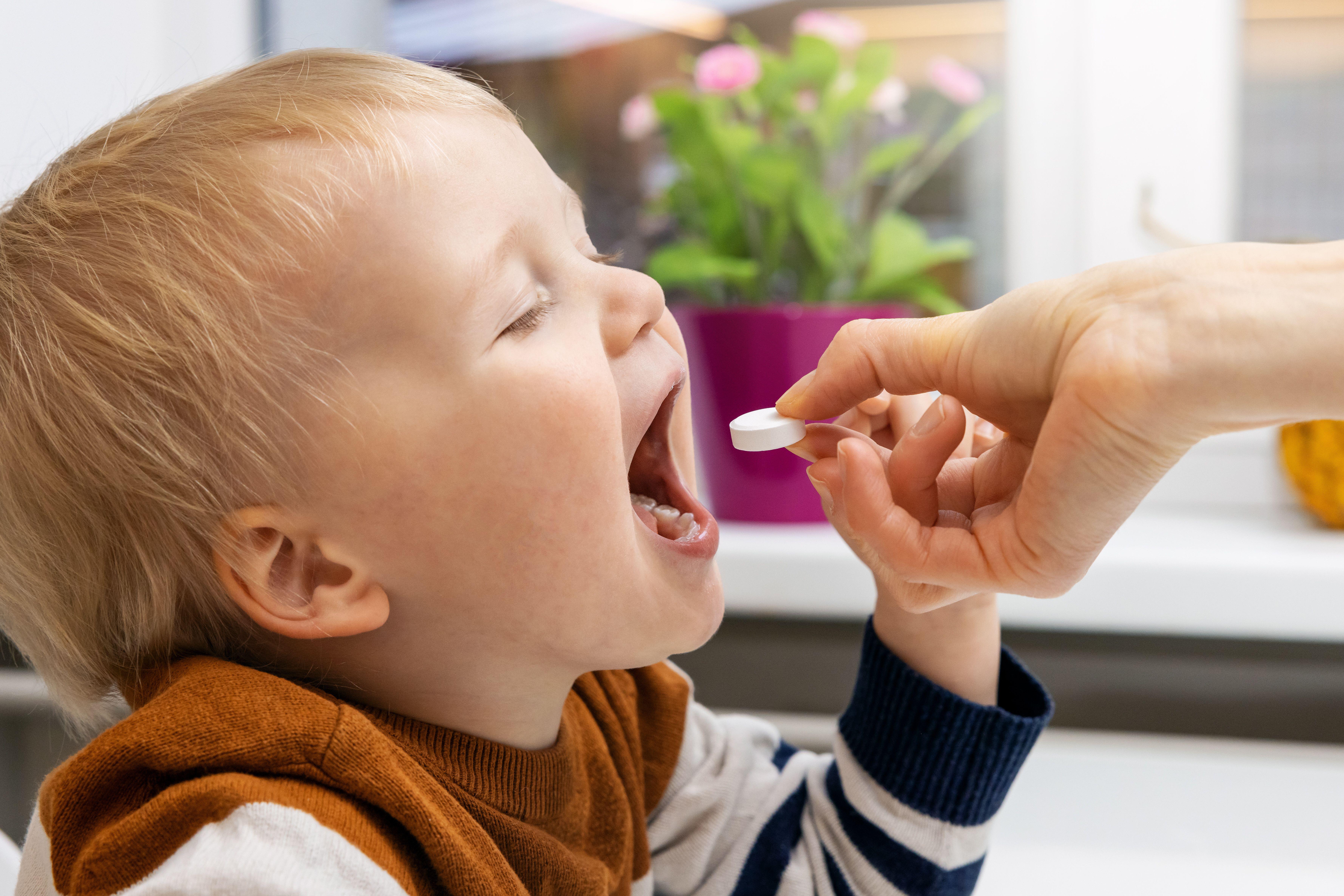 A mother giving a vitamin pill to her child