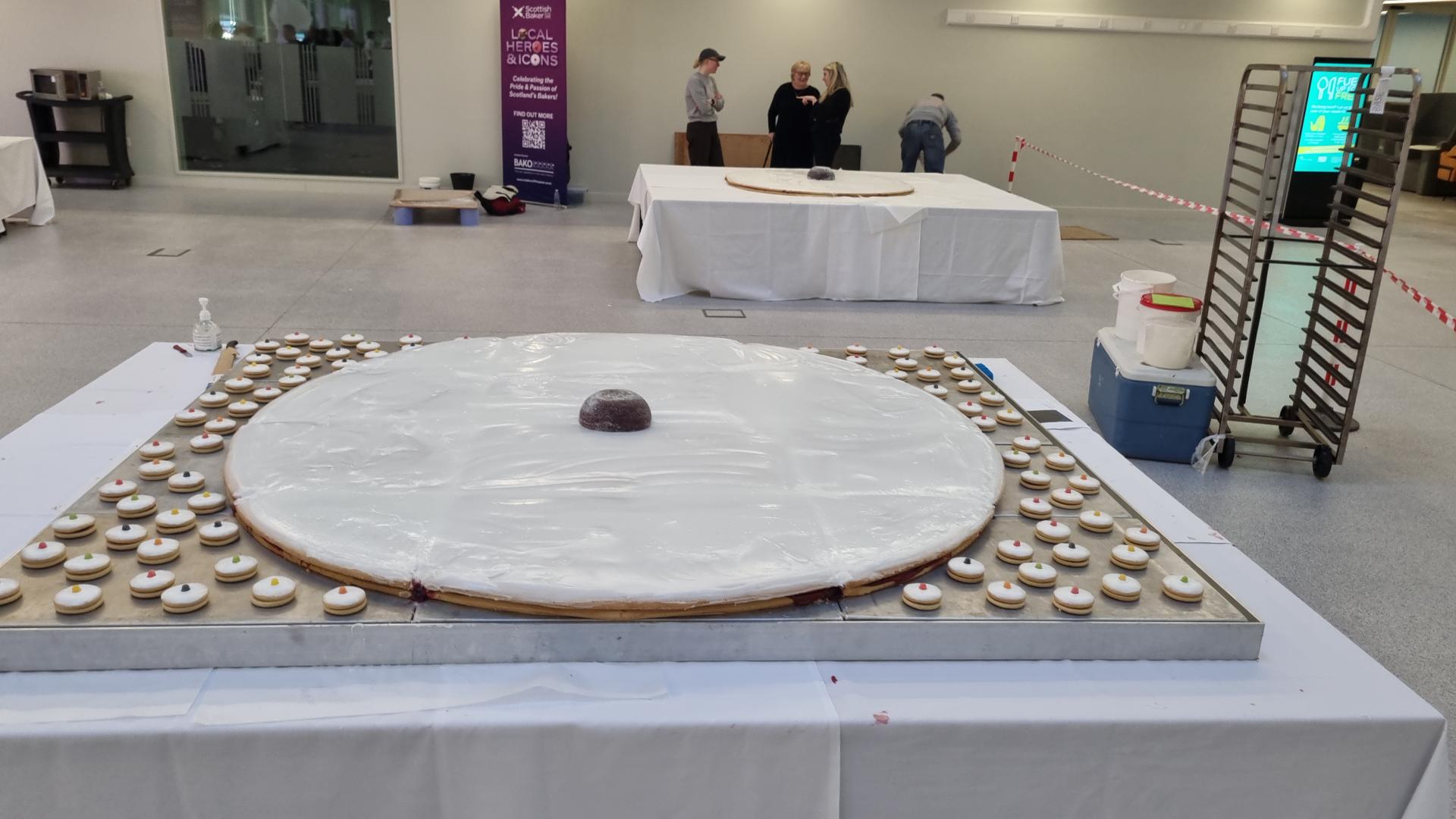 A giant Empire biscuit on a table, surrounded by dozens of smaller versions