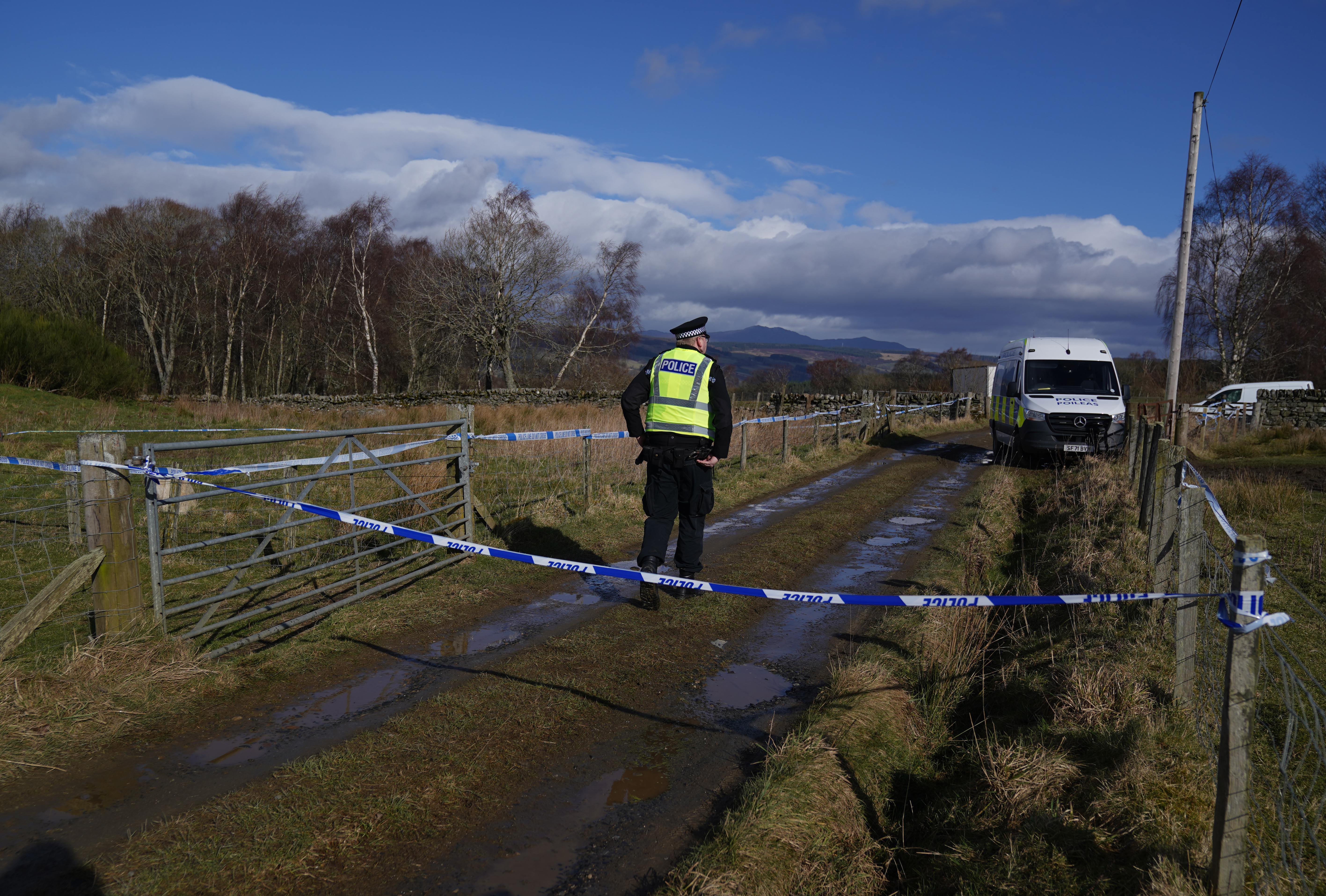 Police tape and a police officer on a country lane