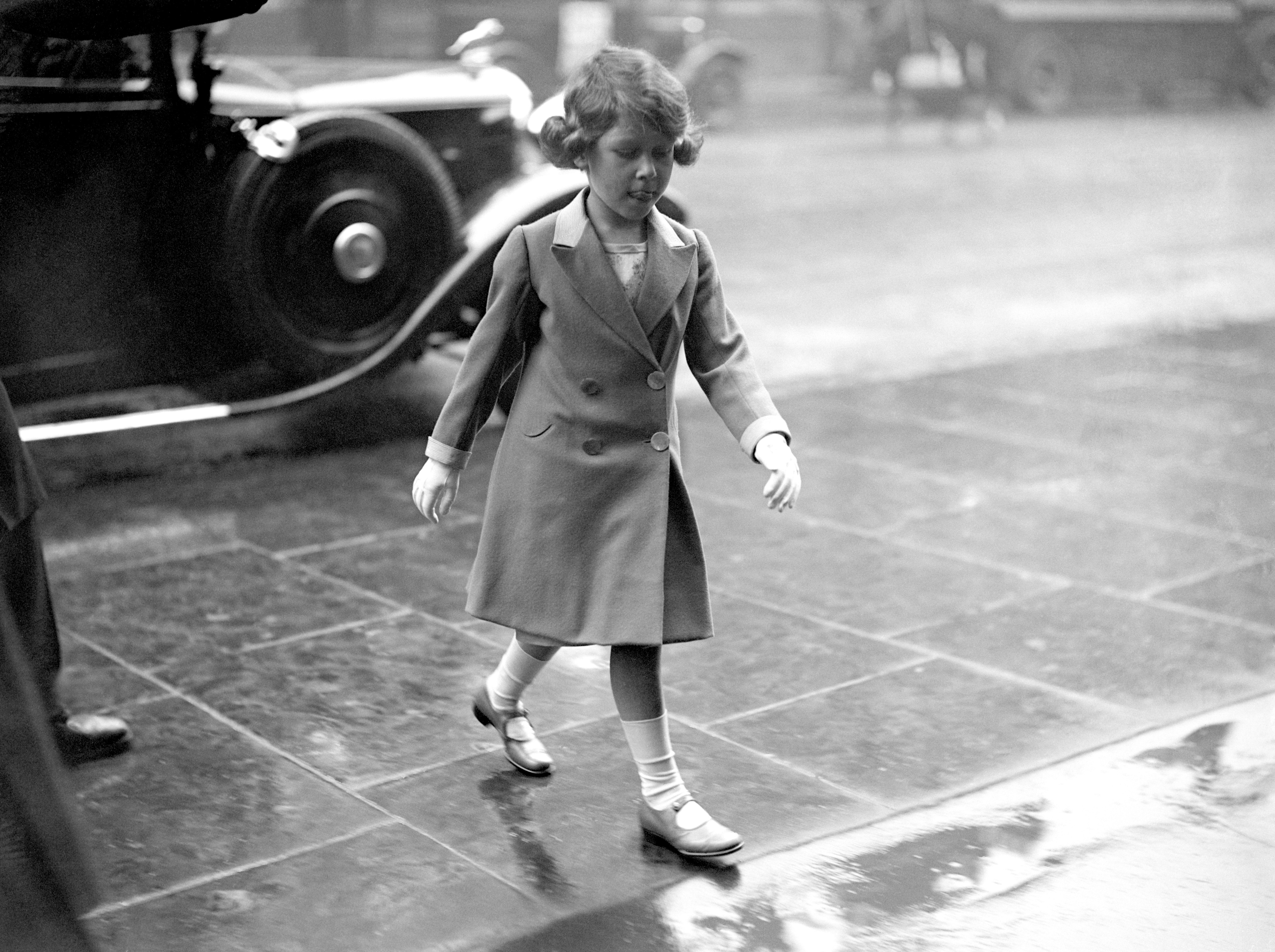 Princess Elizabeth walking bareheaded through the rain to visit the Royal Tournament at Olympia in London.