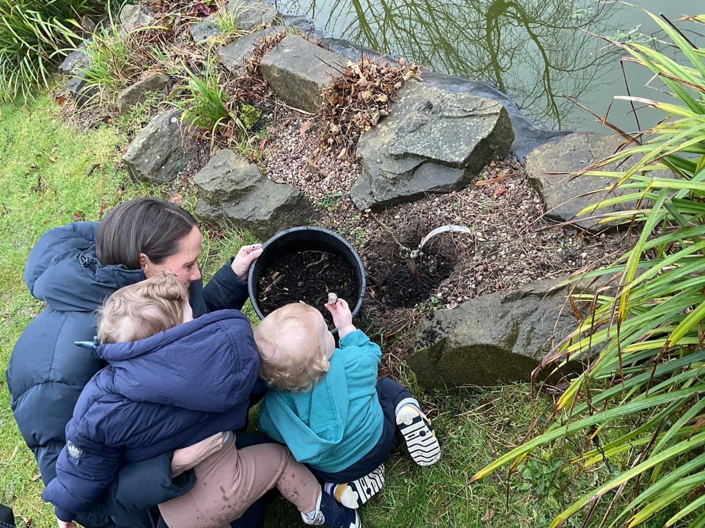 An Action for Children staff member helps two children plant Kate's rose 