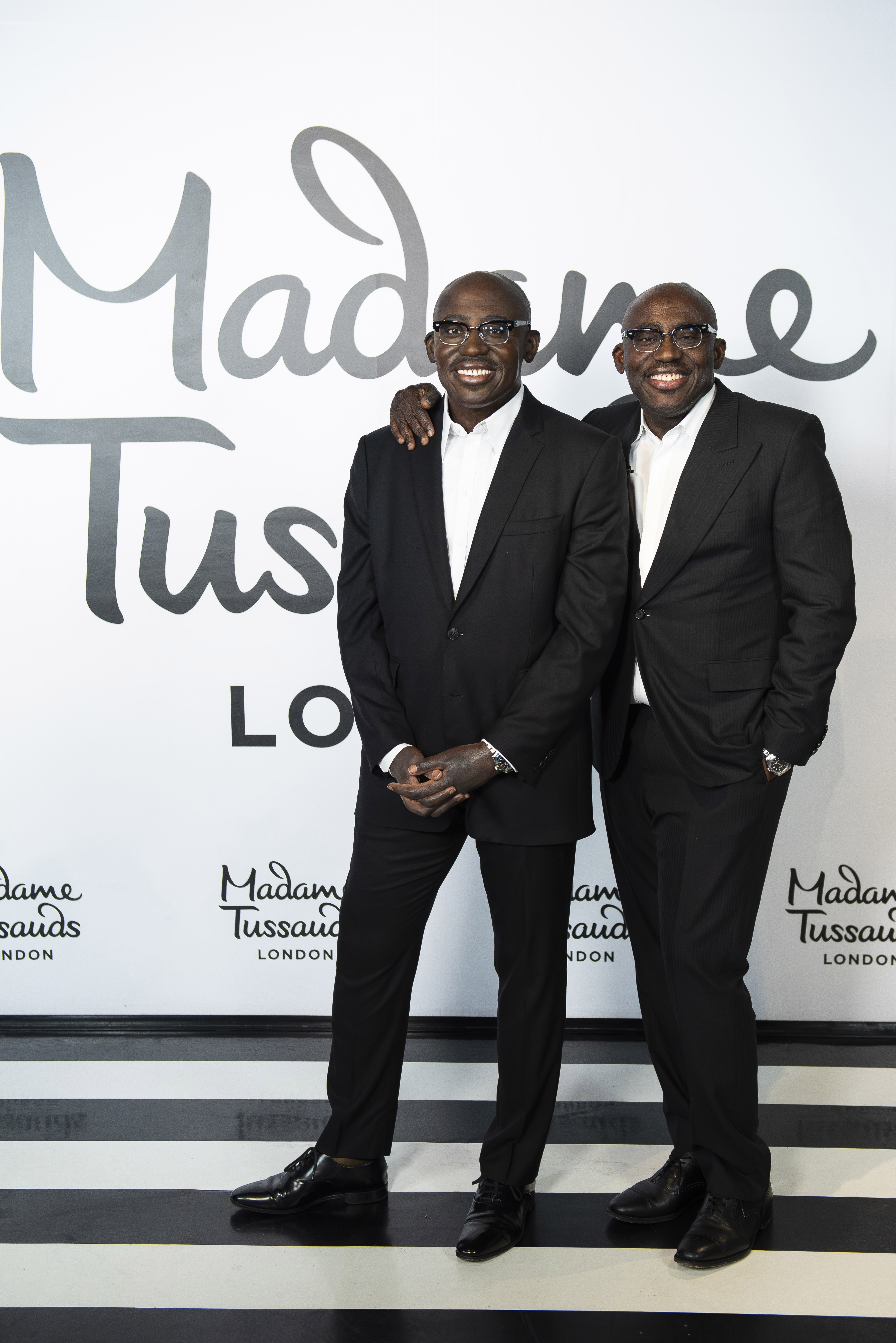 Edward Enninful smiling while standing with his arm round his waxwork model