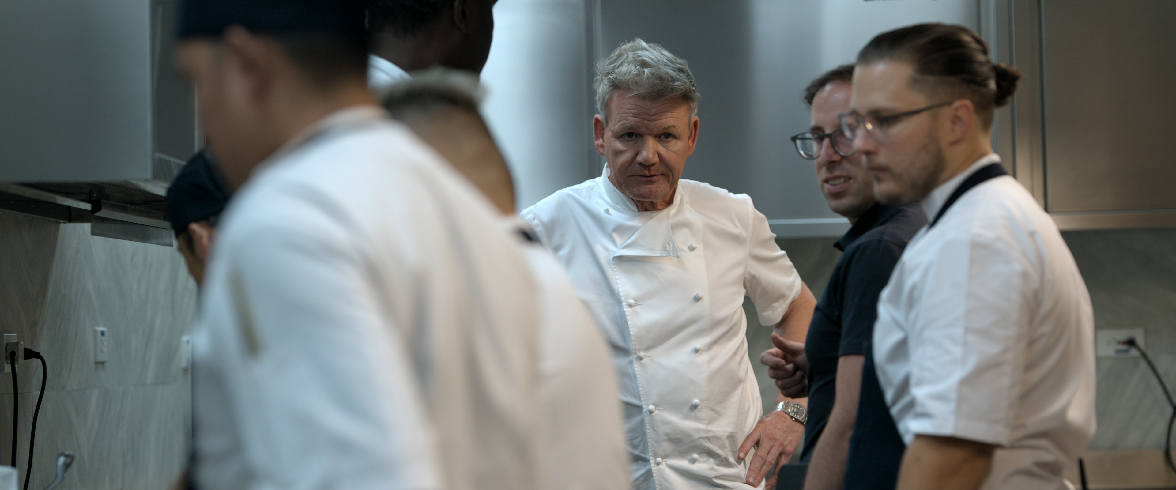 Gordon Ramsay, centre, wearing chef whites in a kitchen with other young chefs