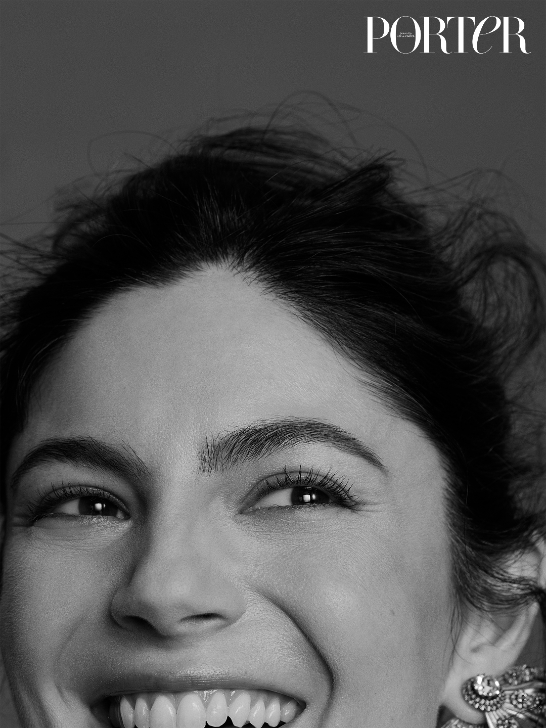 Close-up black and white headshot of Monica Barbaro smiling, with Porter written in the top right-hand corner of the image
