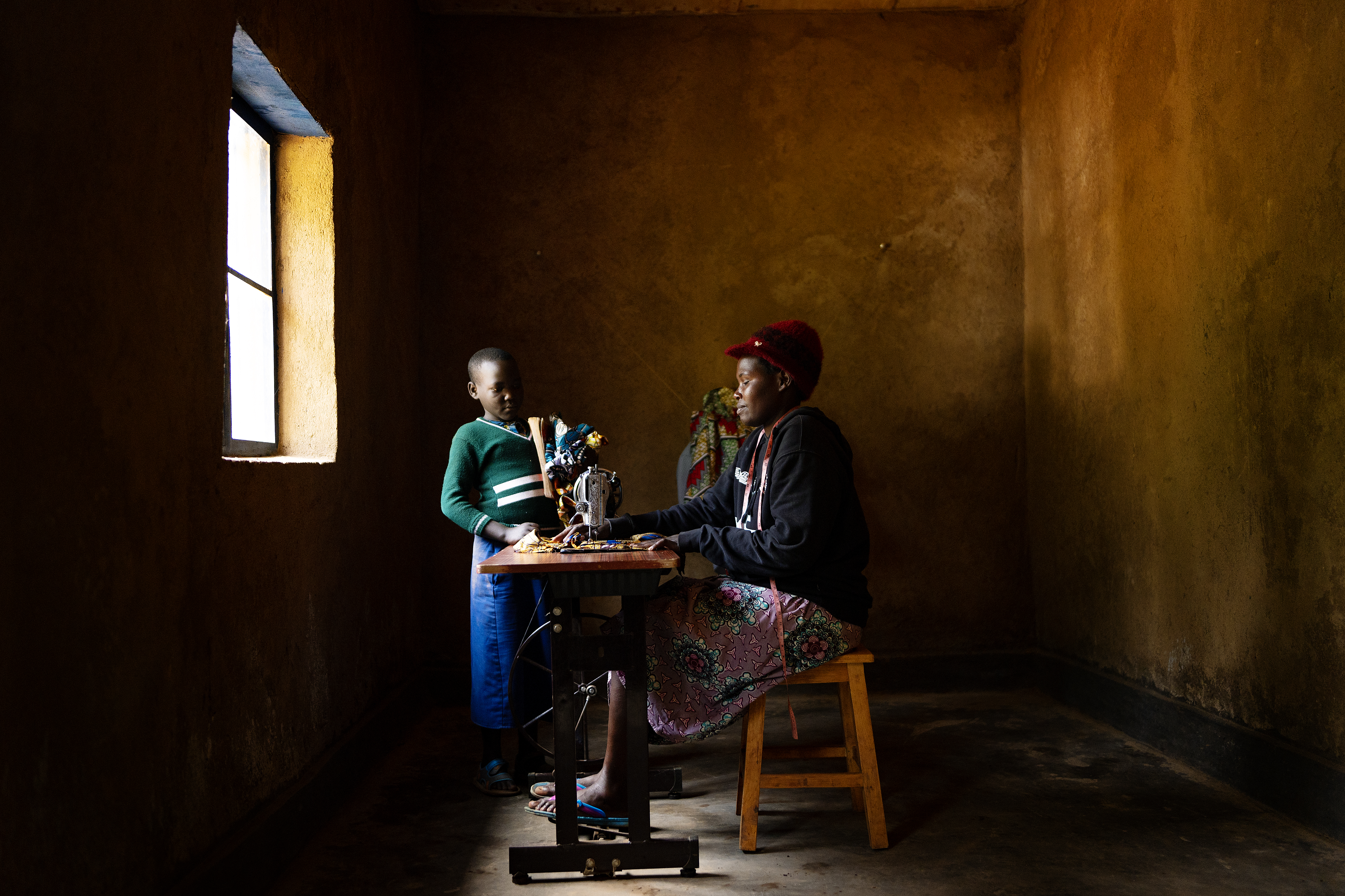 Uwamahoro Uwitonze using a sewing machine in her rebuilt home