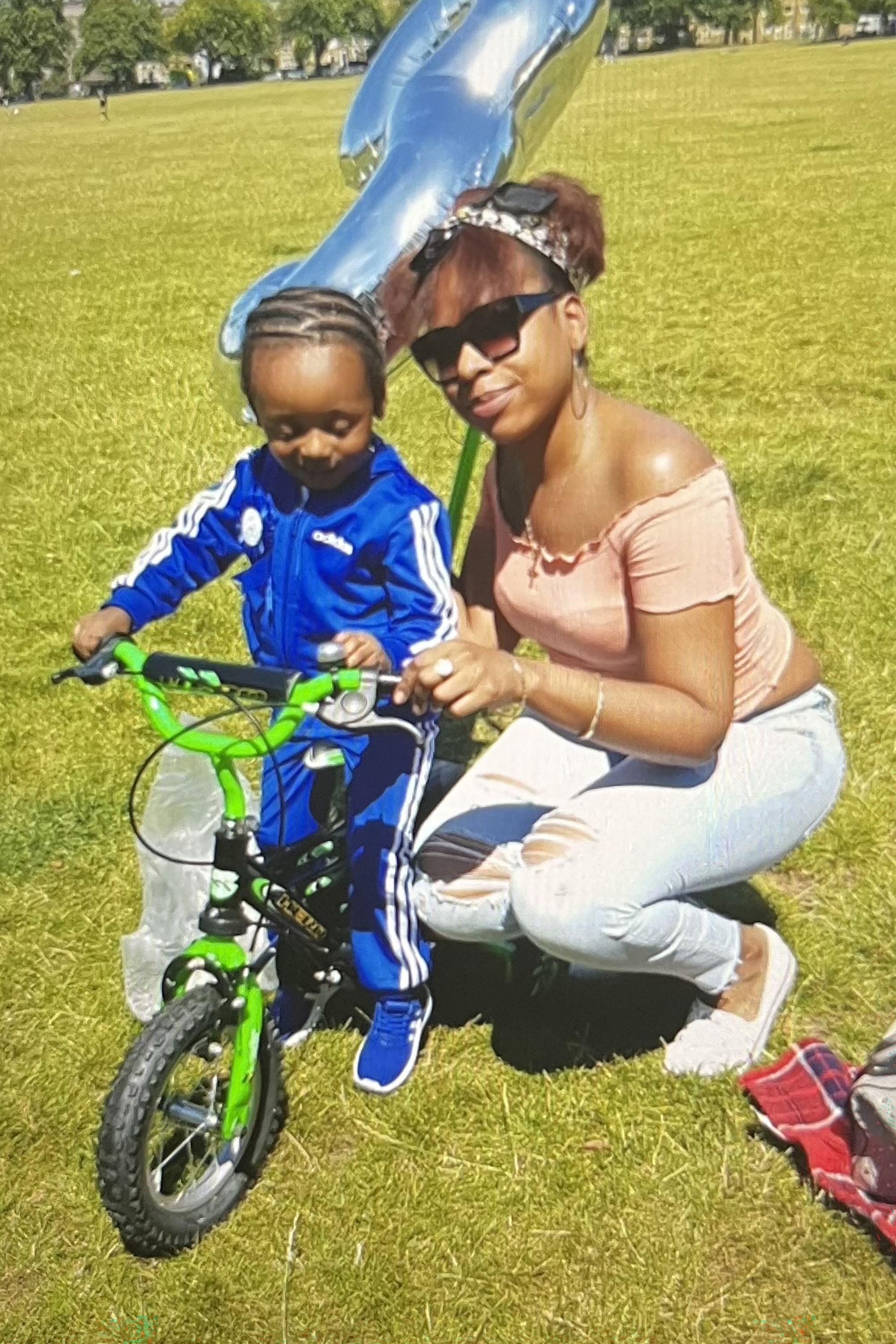 Aleisha Rochester crouching down next to her son Xavier who is sitting on a bike