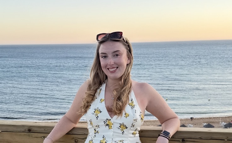 Ellie Crozier smiling, with the seat and sunset behind her