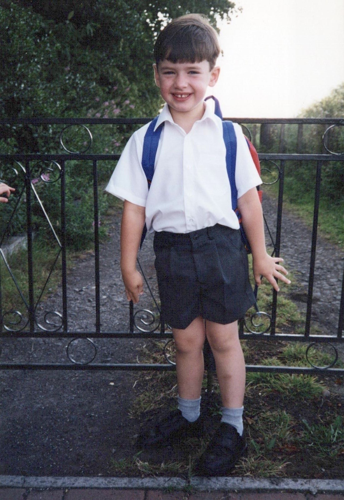 Ross Irvine smiling while dressed in school uniform and carrying a rucksack on his back