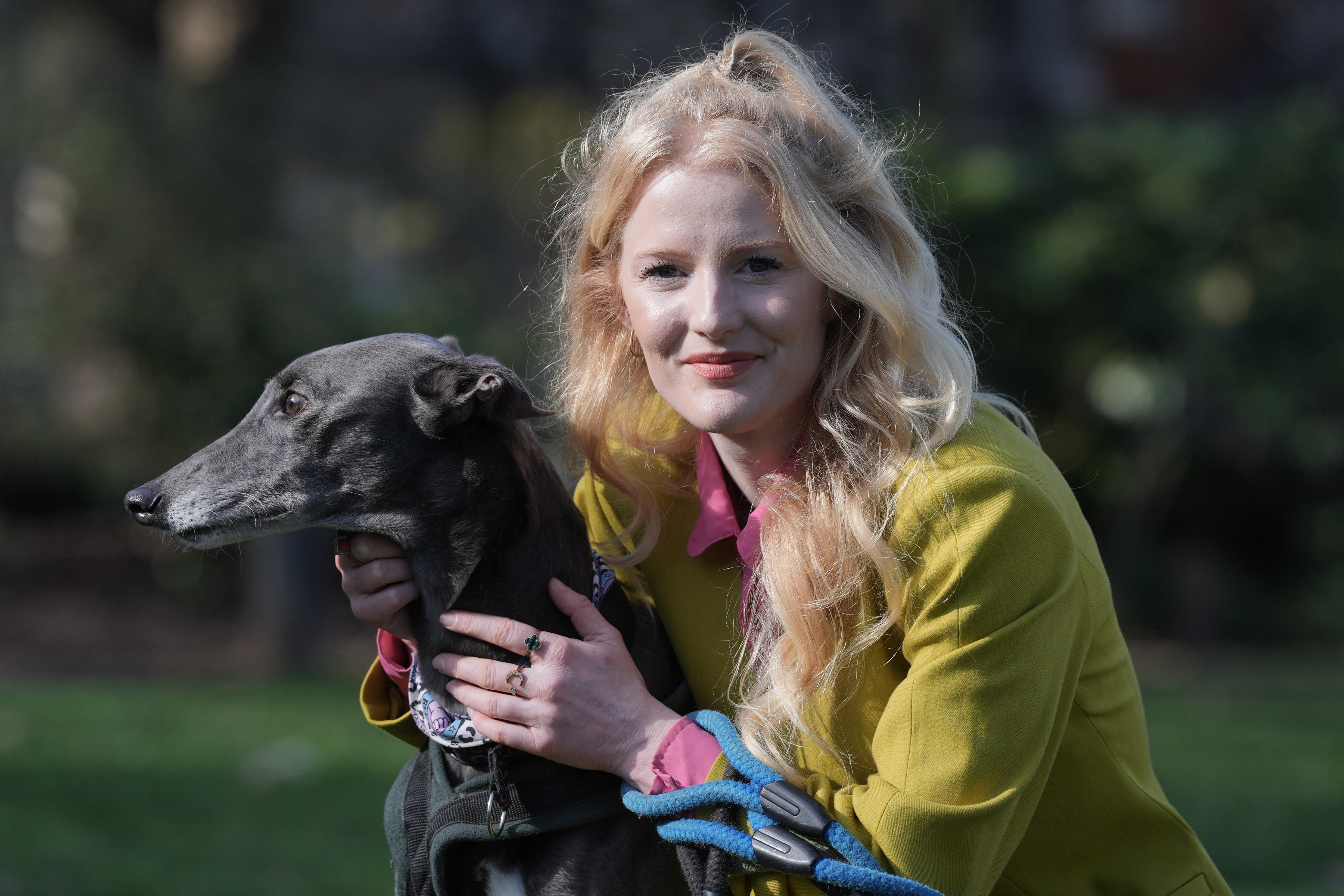 Green MP Hannah Spencer smiling while cuddling a greyhound