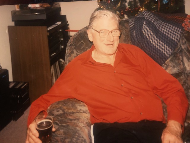 Photo dated 1996 of David Rollo in an arm chair, holding a drink