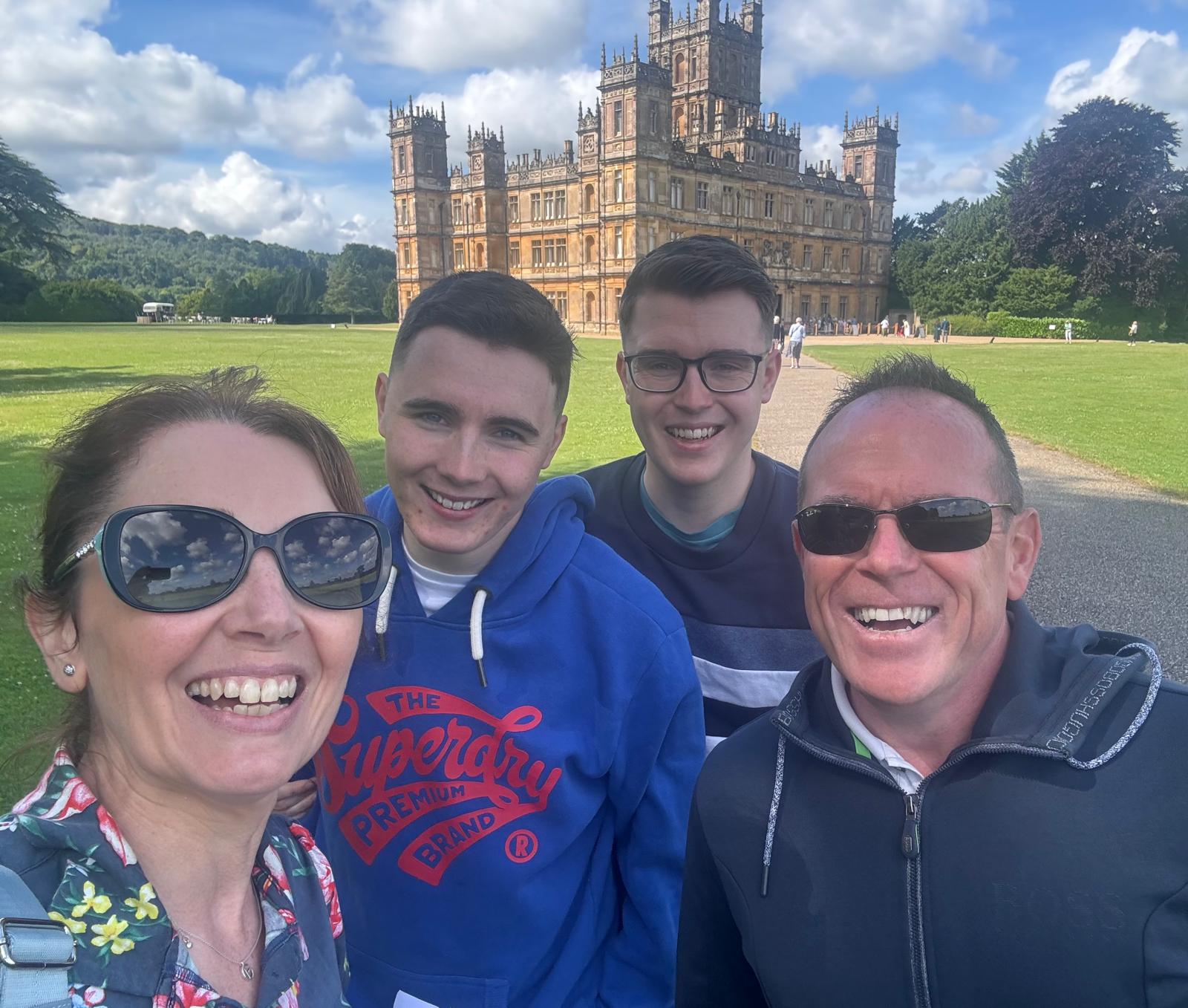 Gaynor Simpson, Stuart Simpson, Ross Simpson and Scott Simpson smiling for a selfie outside, in front of a large manor