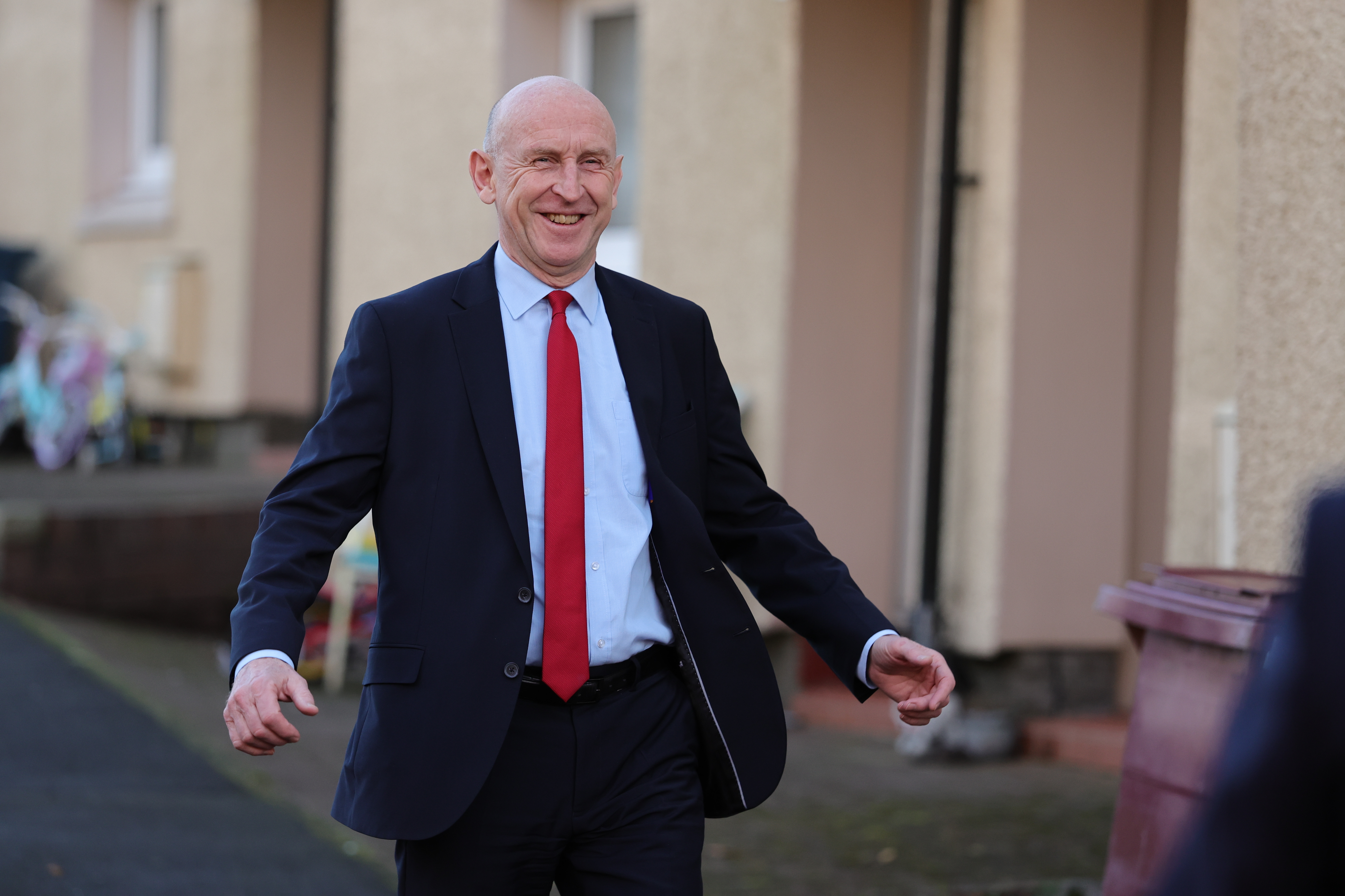 John Healey smiling while walking down a street